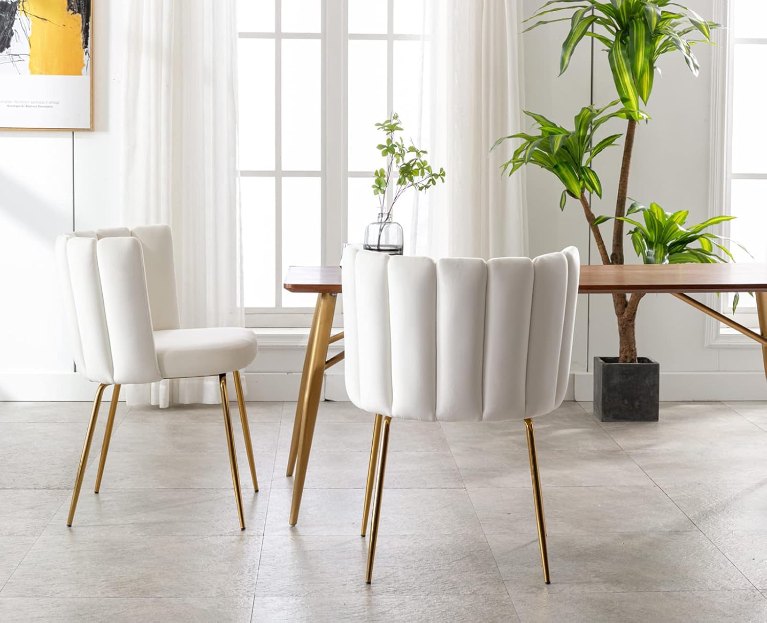 Modern dining room with white chairs and a wooden table, featuring plants and light decor.