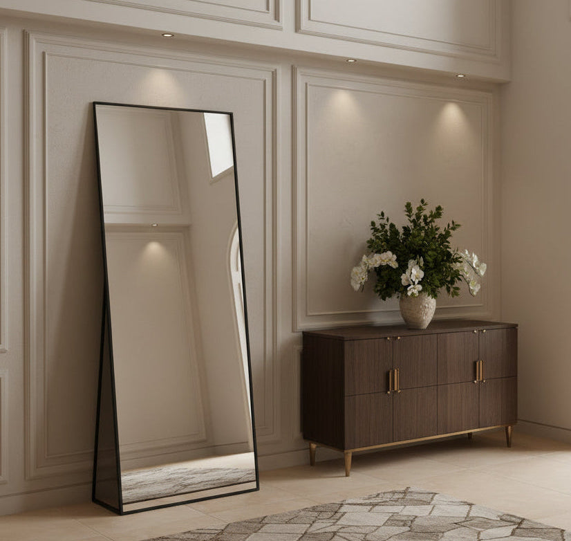 Full-length mirror leaning against a wall in a bedroom setting.