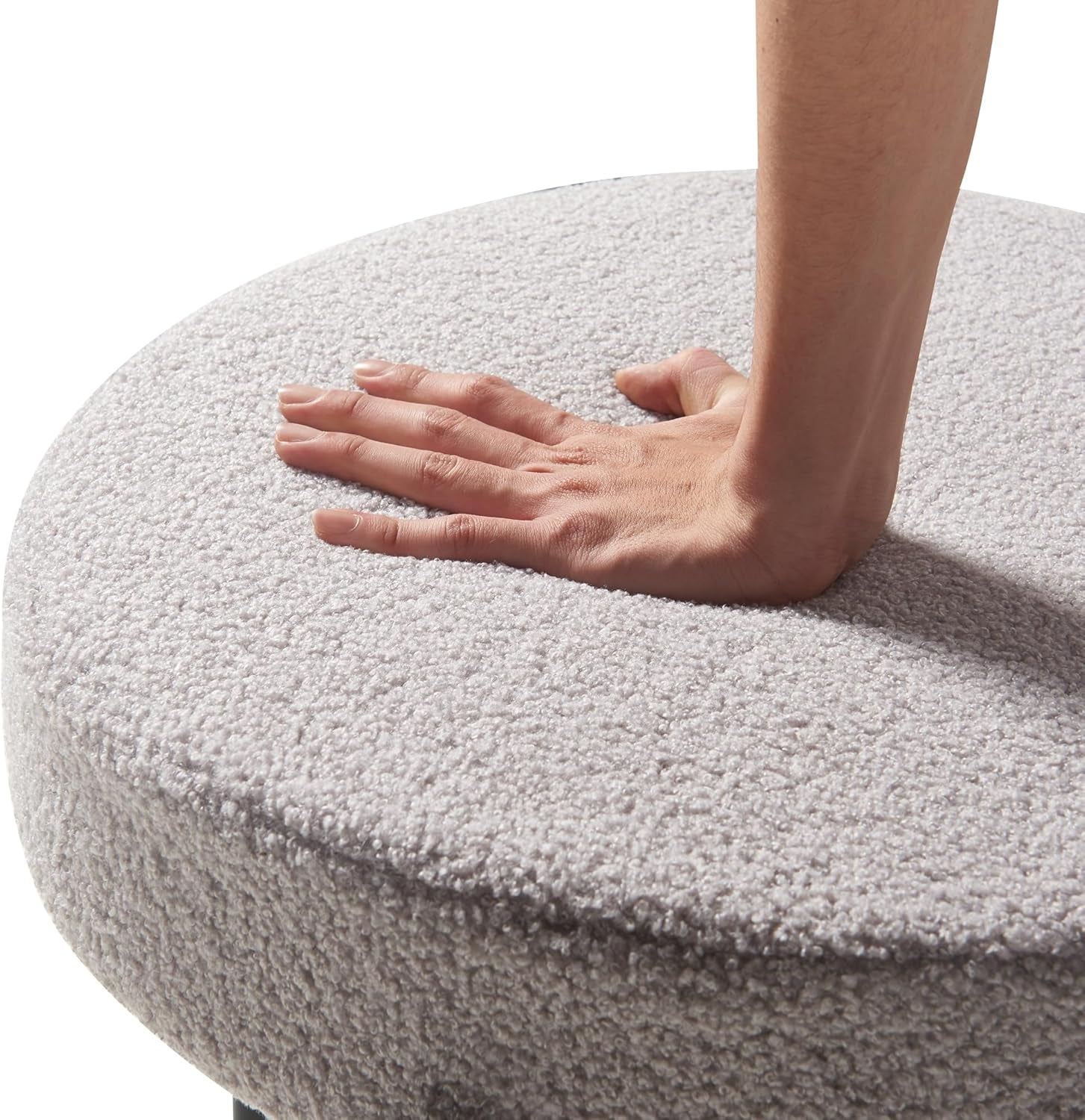 Round gray cushion with a hand resting on it against a white background