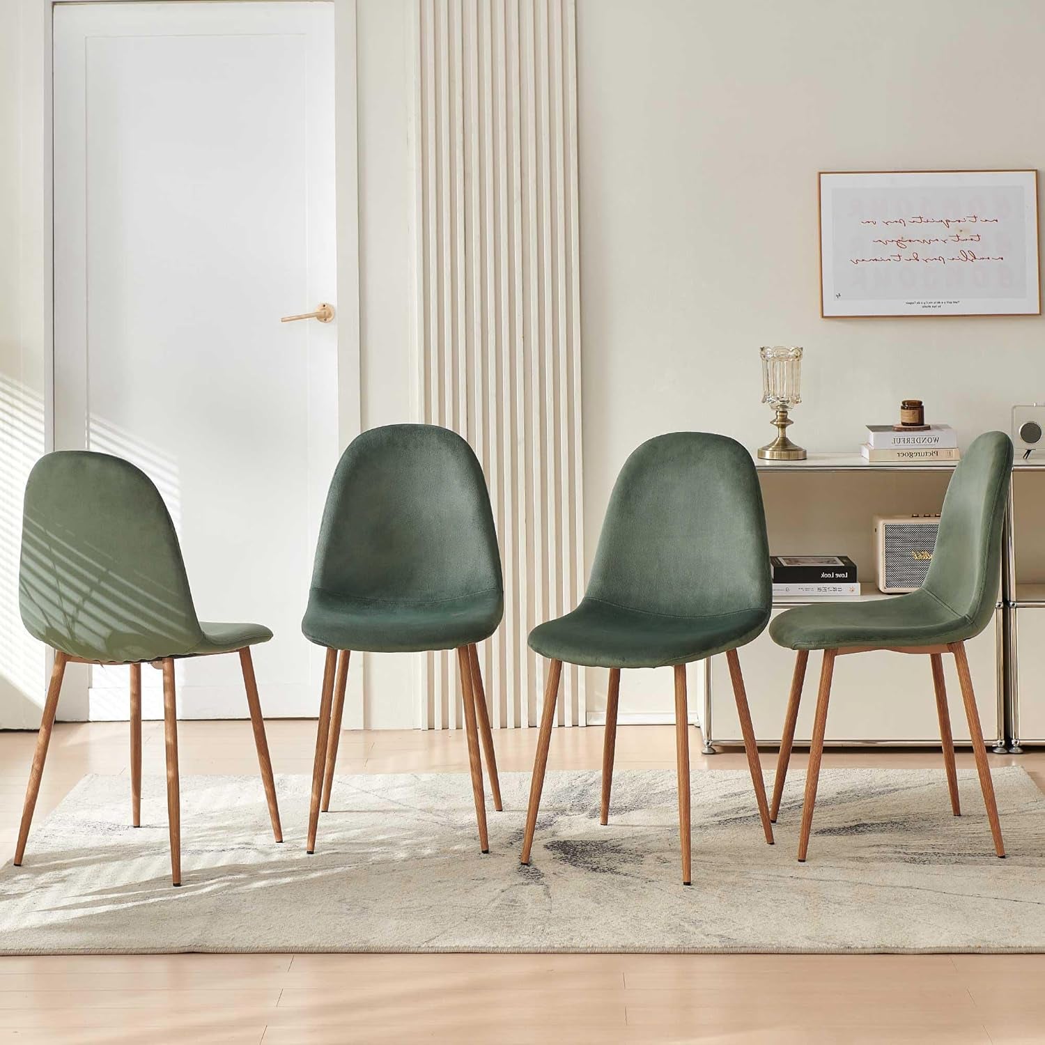 Four green chairs with wooden legs arranged in a room with a desk and decor.