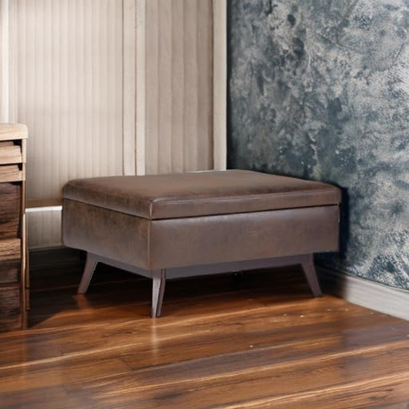 Brown leather ottoman against a textured wall and wooden floor.