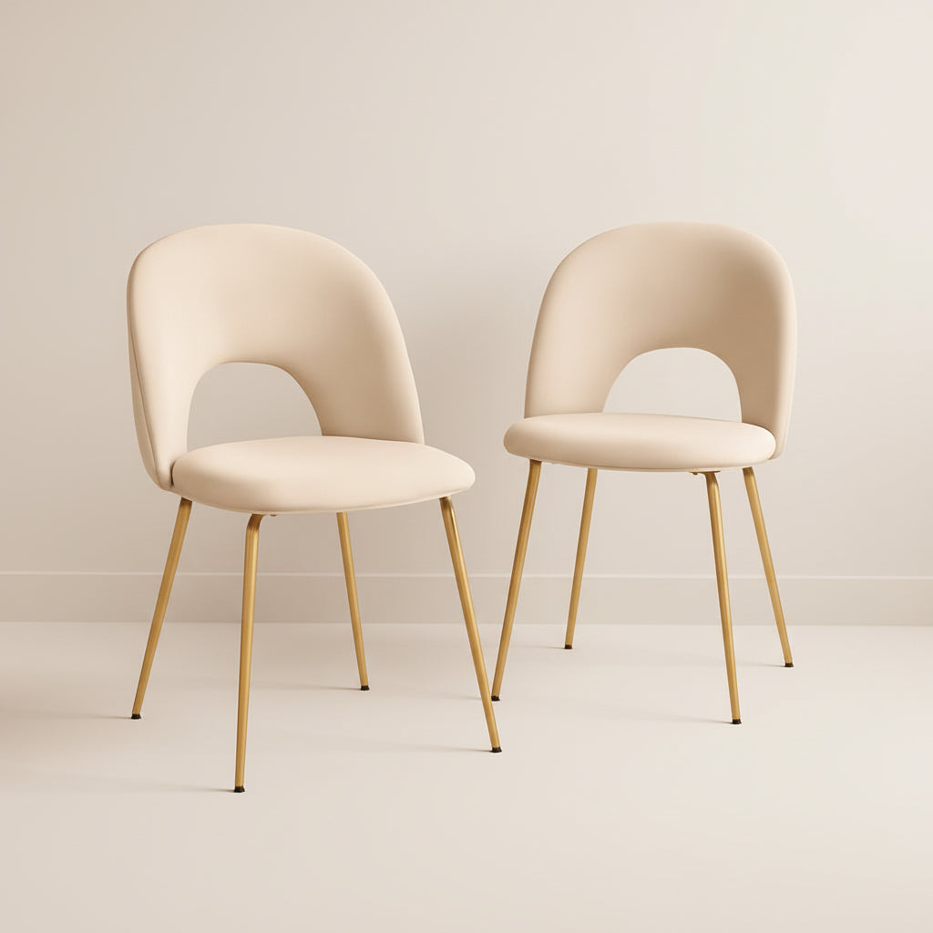 Two beige chairs with gold legs in a room with a warm color scheme.