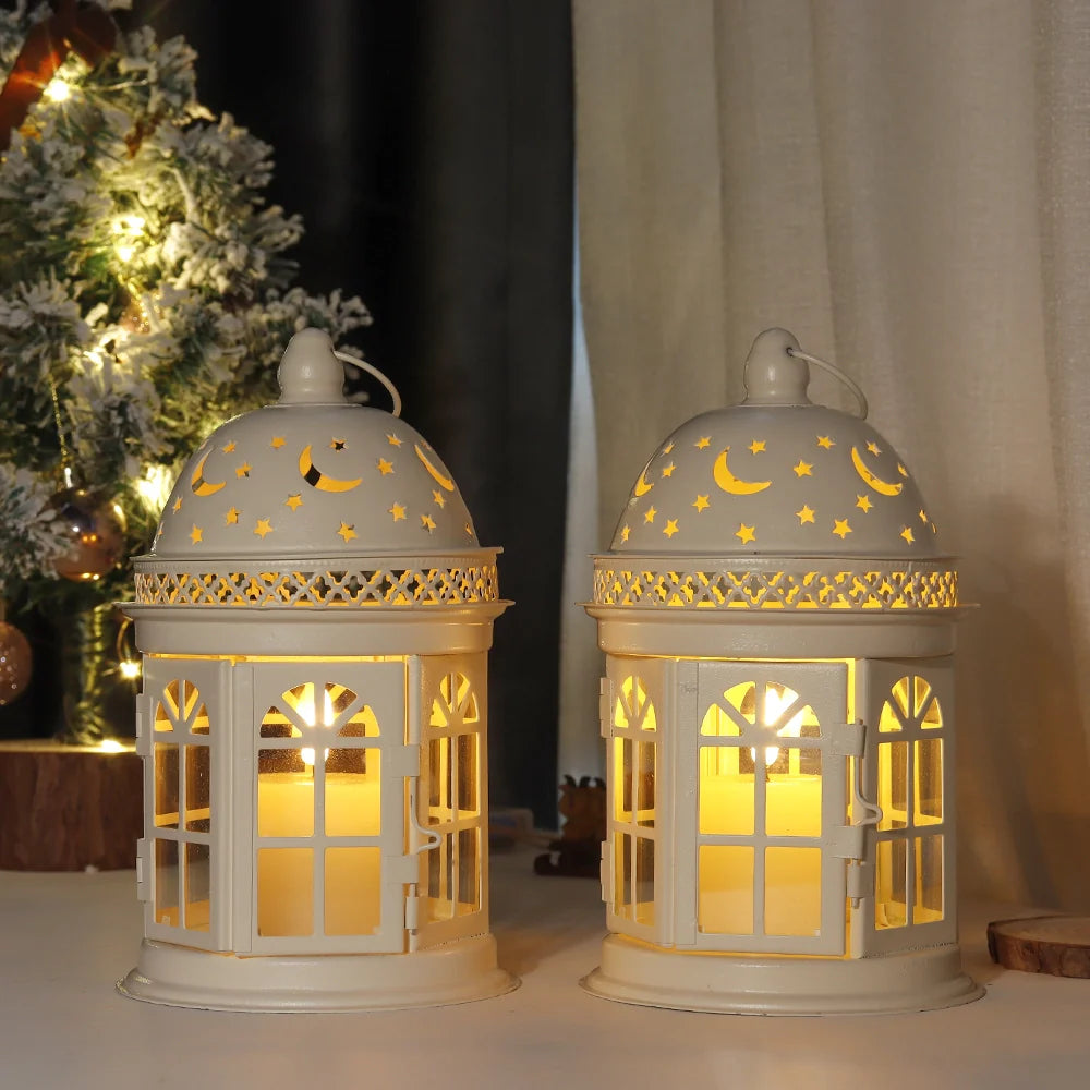 Two decorative lanterns with star and moon patterns on a surface with a Christmas tree in the background.
