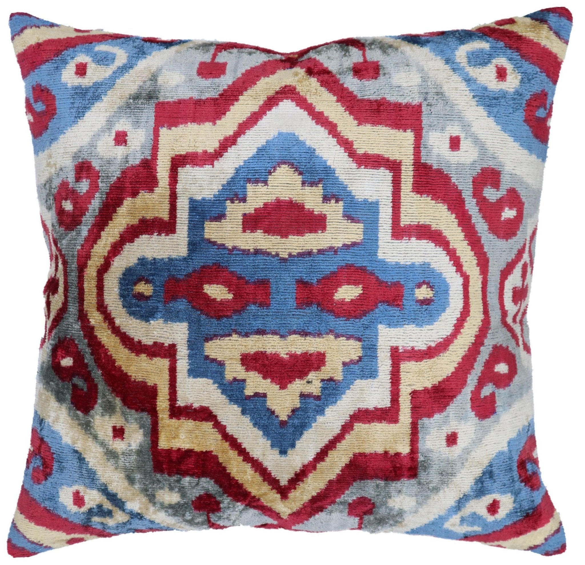 Decorative pillow with a geometric pattern in red, blue, and beige on a white background