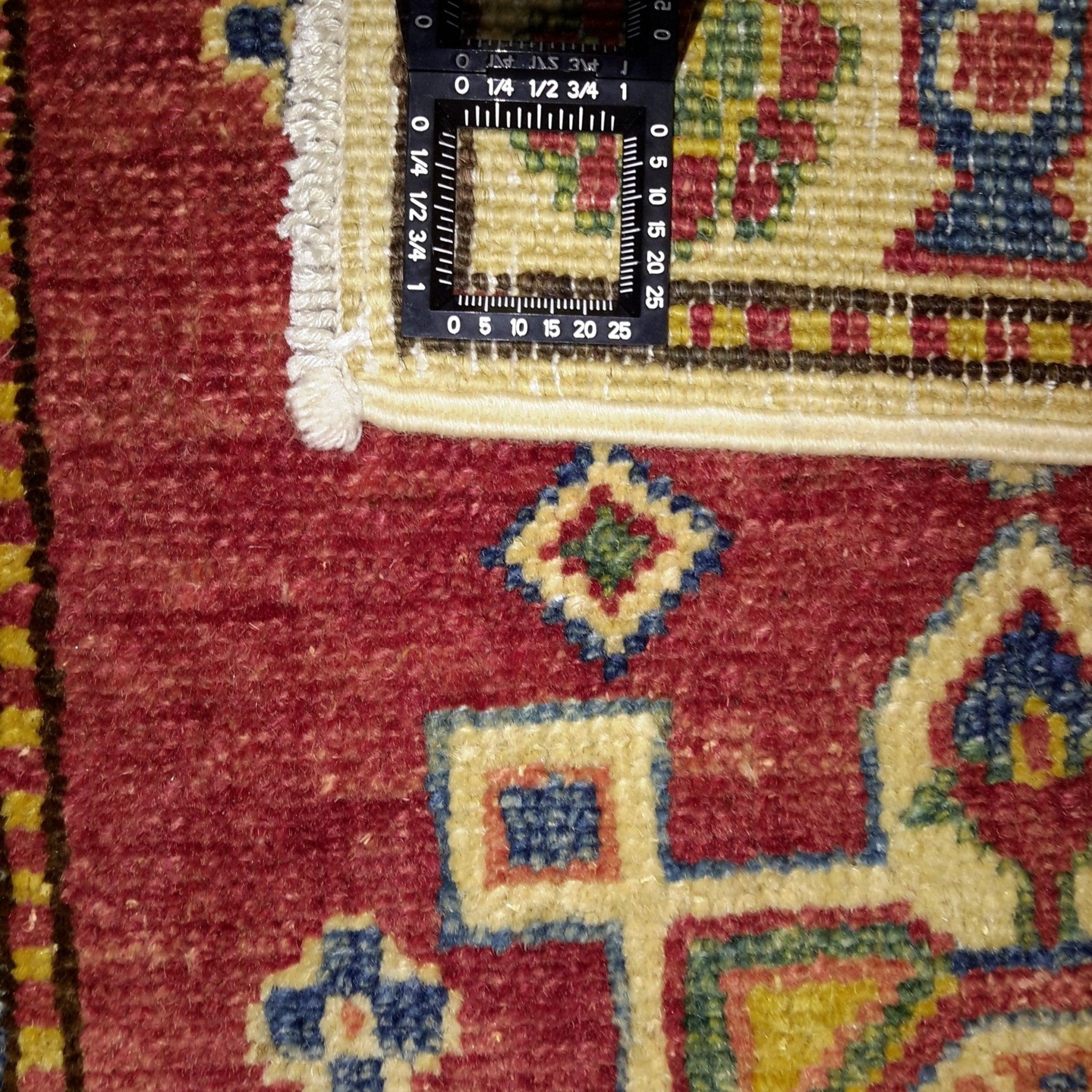 Close-up of a patterned rug with a ruler overlay for scale.
