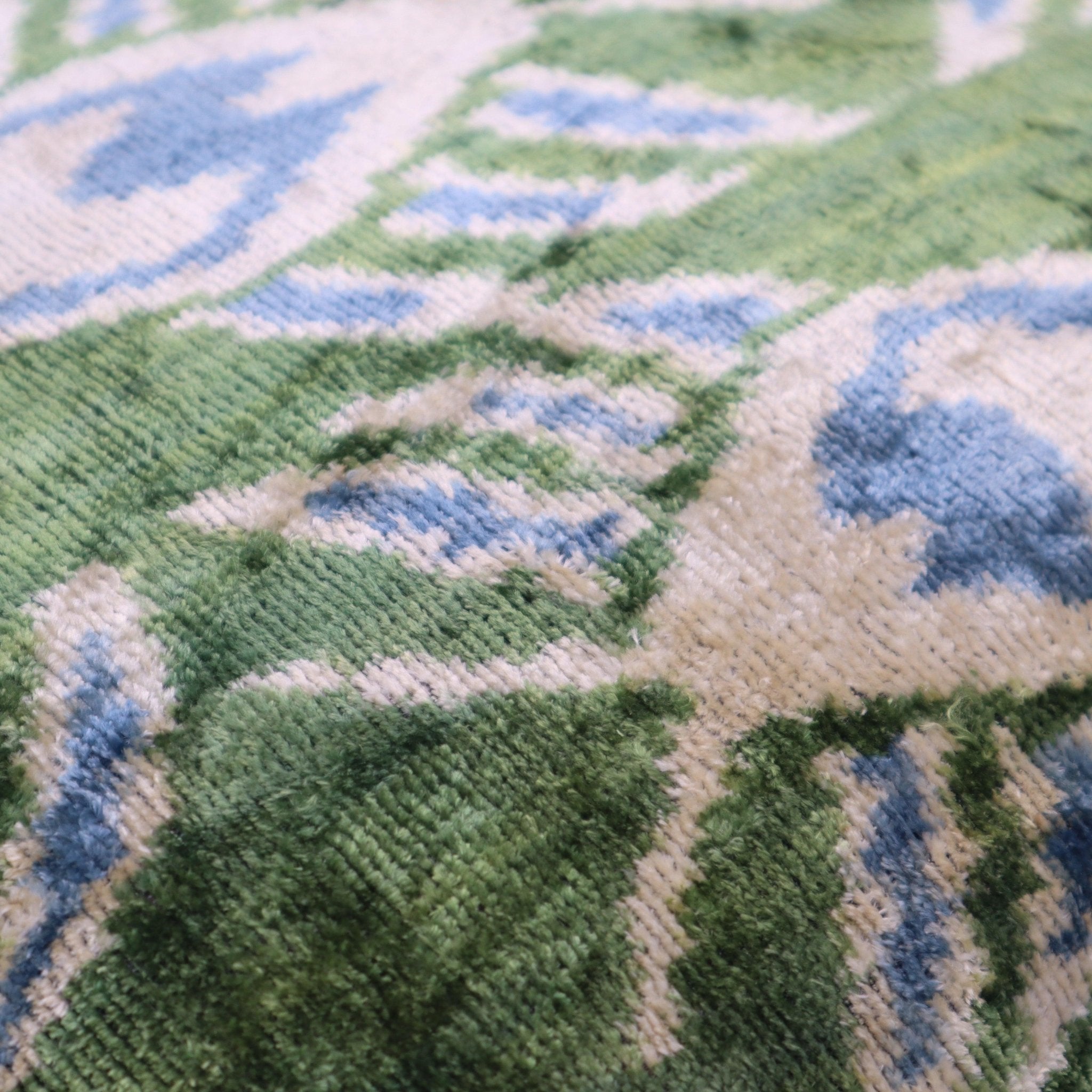 Close-up of a textured fabric with green, blue, and beige pattern