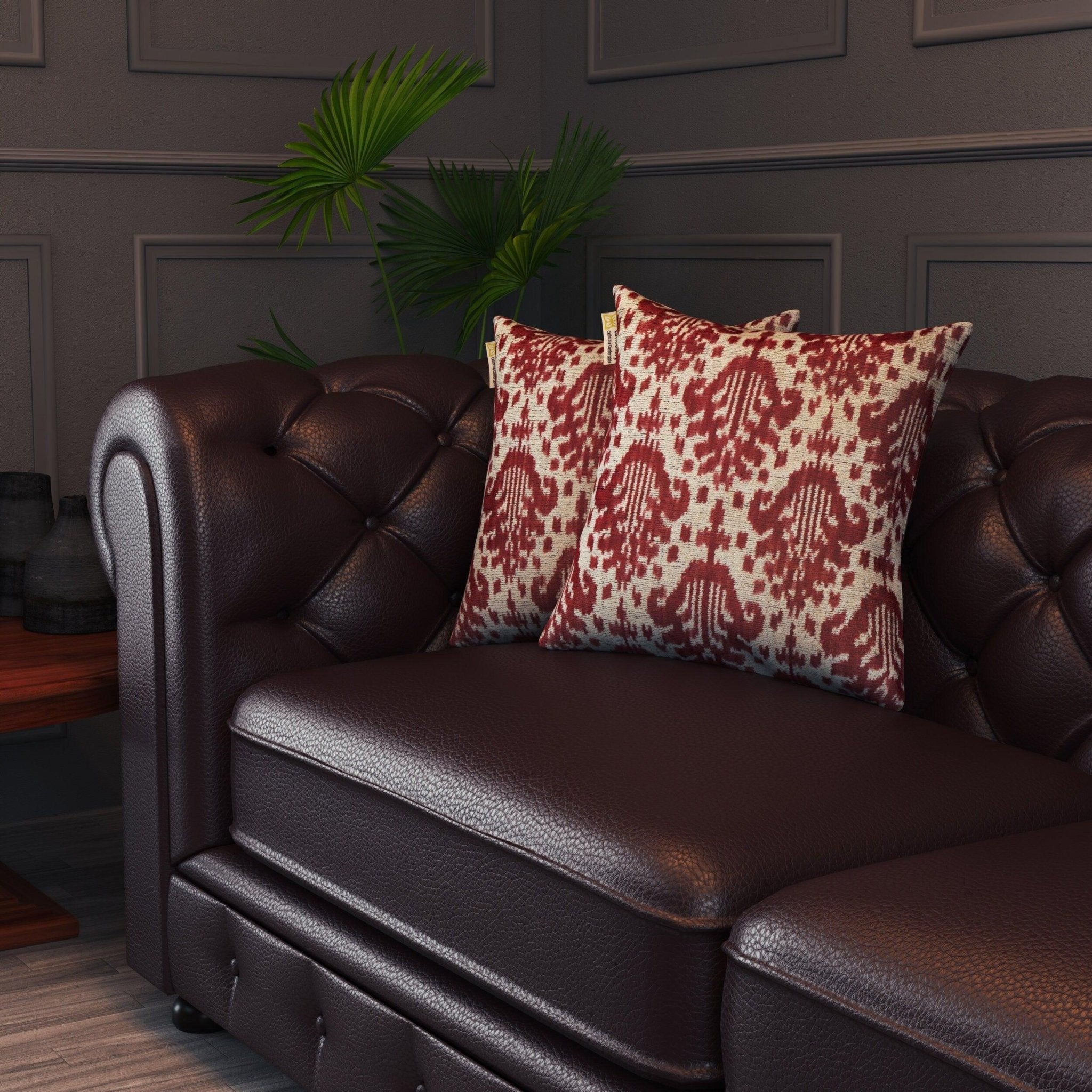 Brown leather sofa with red and beige patterned cushions against a dark paneled wall.