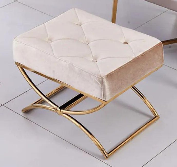 Beige ottoman with gold metal frame on a white tiled floor