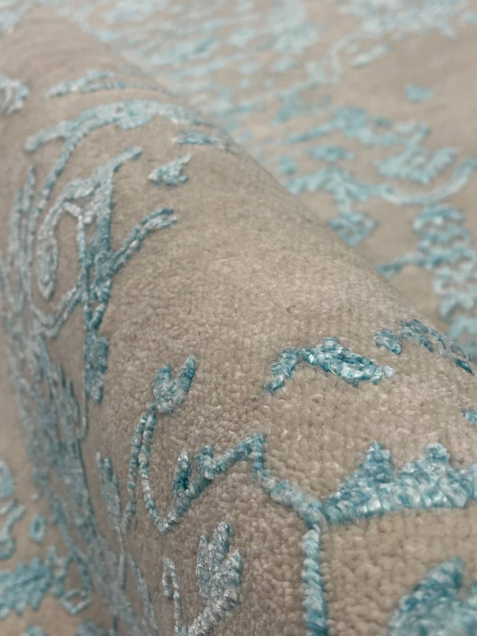 Close-up of a textured fabric with metallic blue designs on a beige background