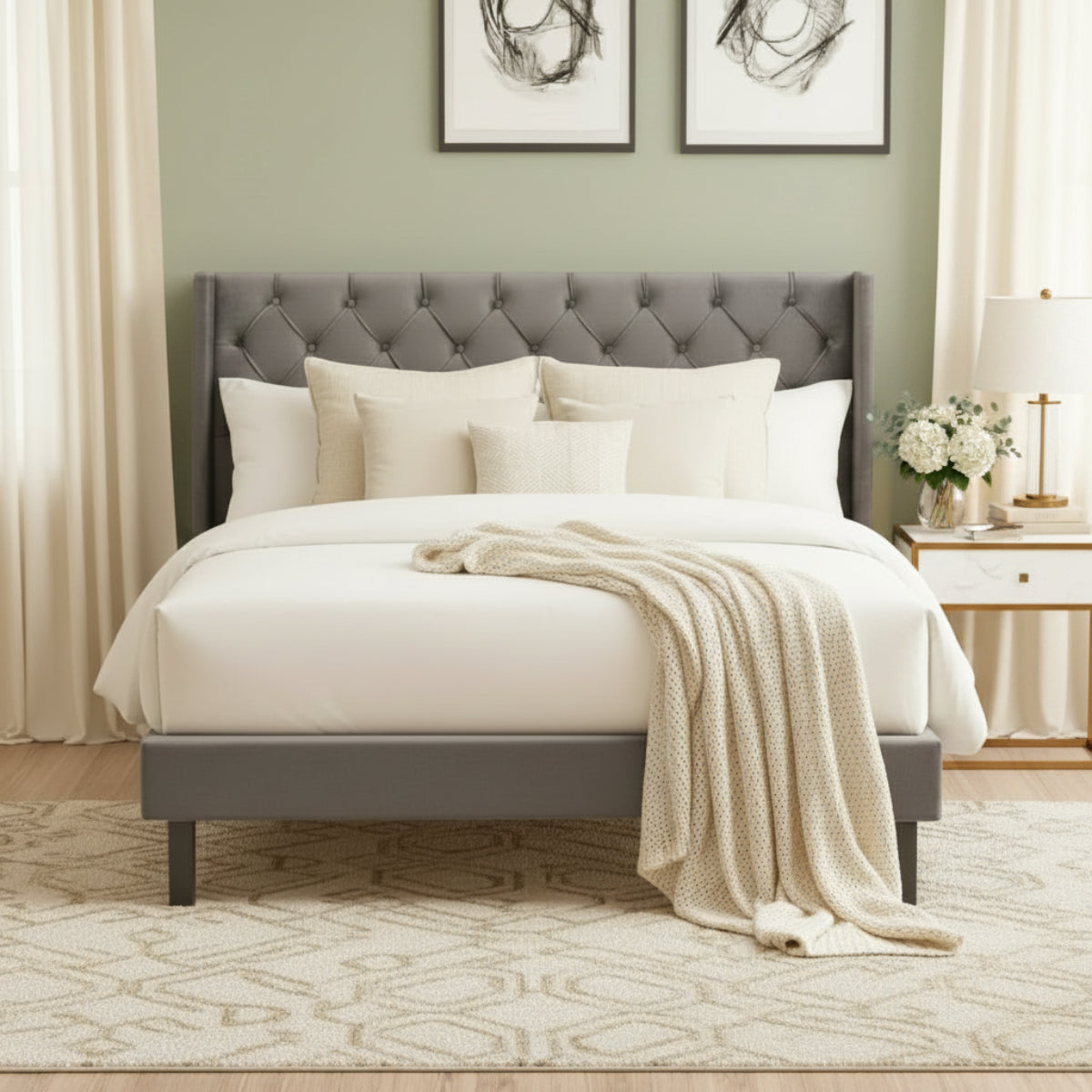 Gray tufted bed with white bedding and a green blanket in a bedroom setting.