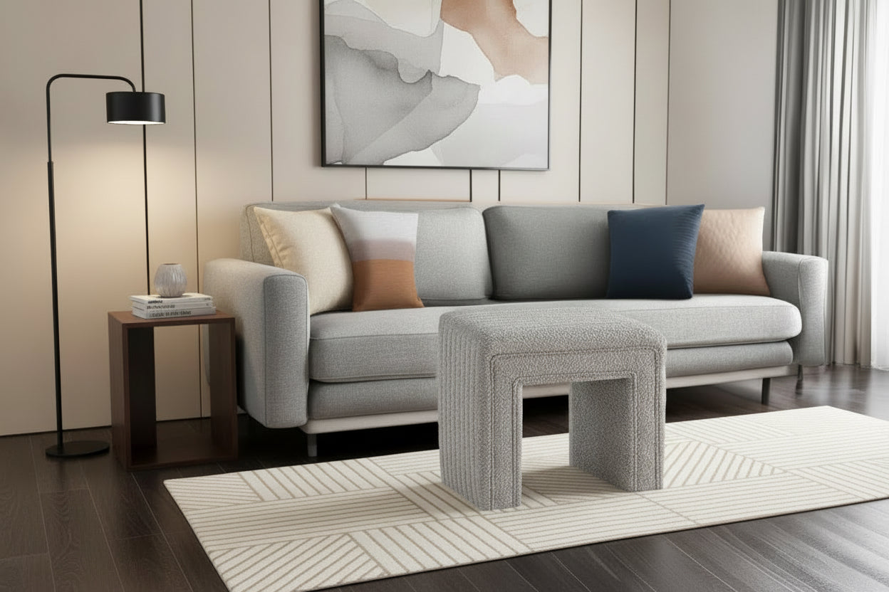 Gray sofa with decorative pillows and a matching ottoman in a modern living room.
