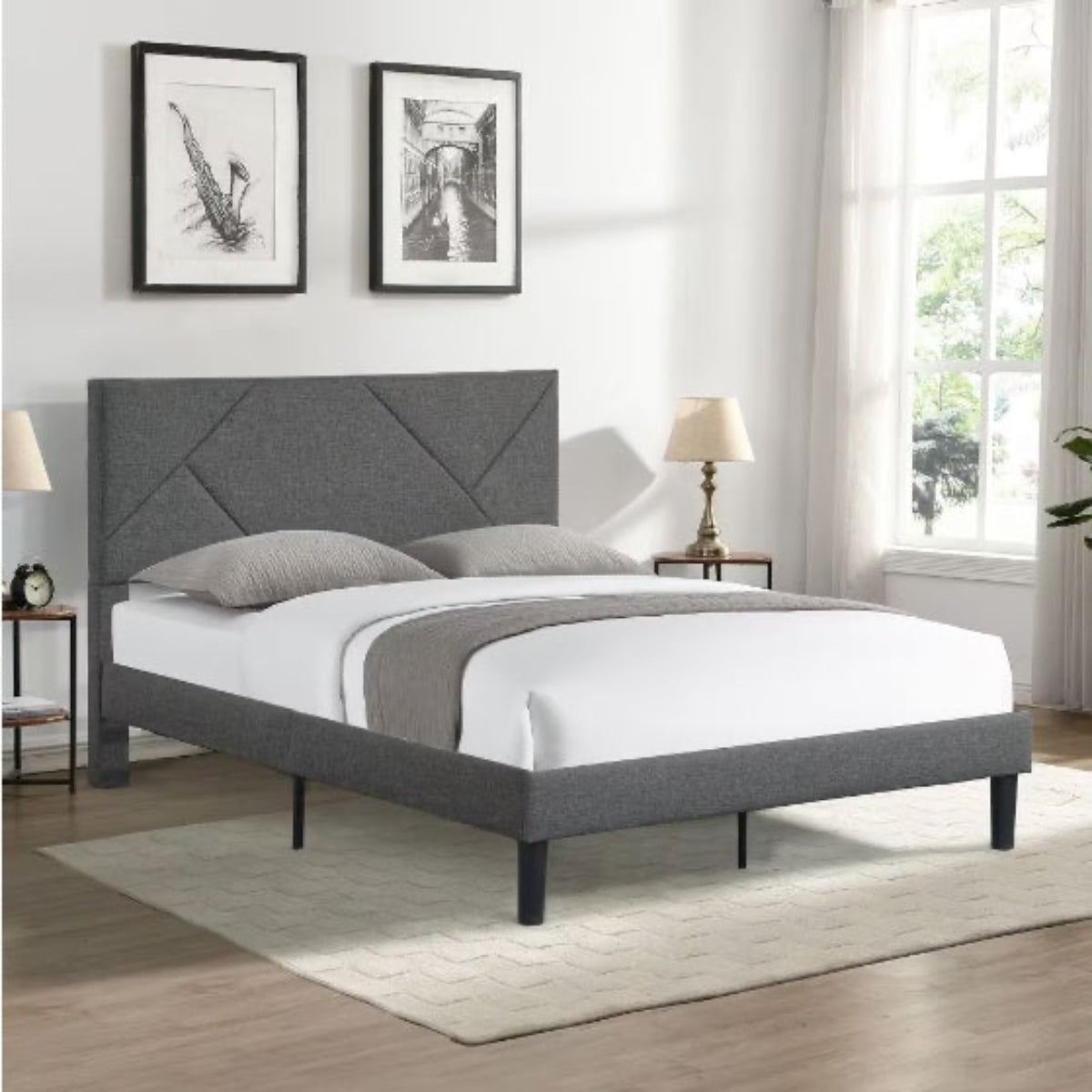 Gray upholstered bed in a bedroom with white walls and a window.
