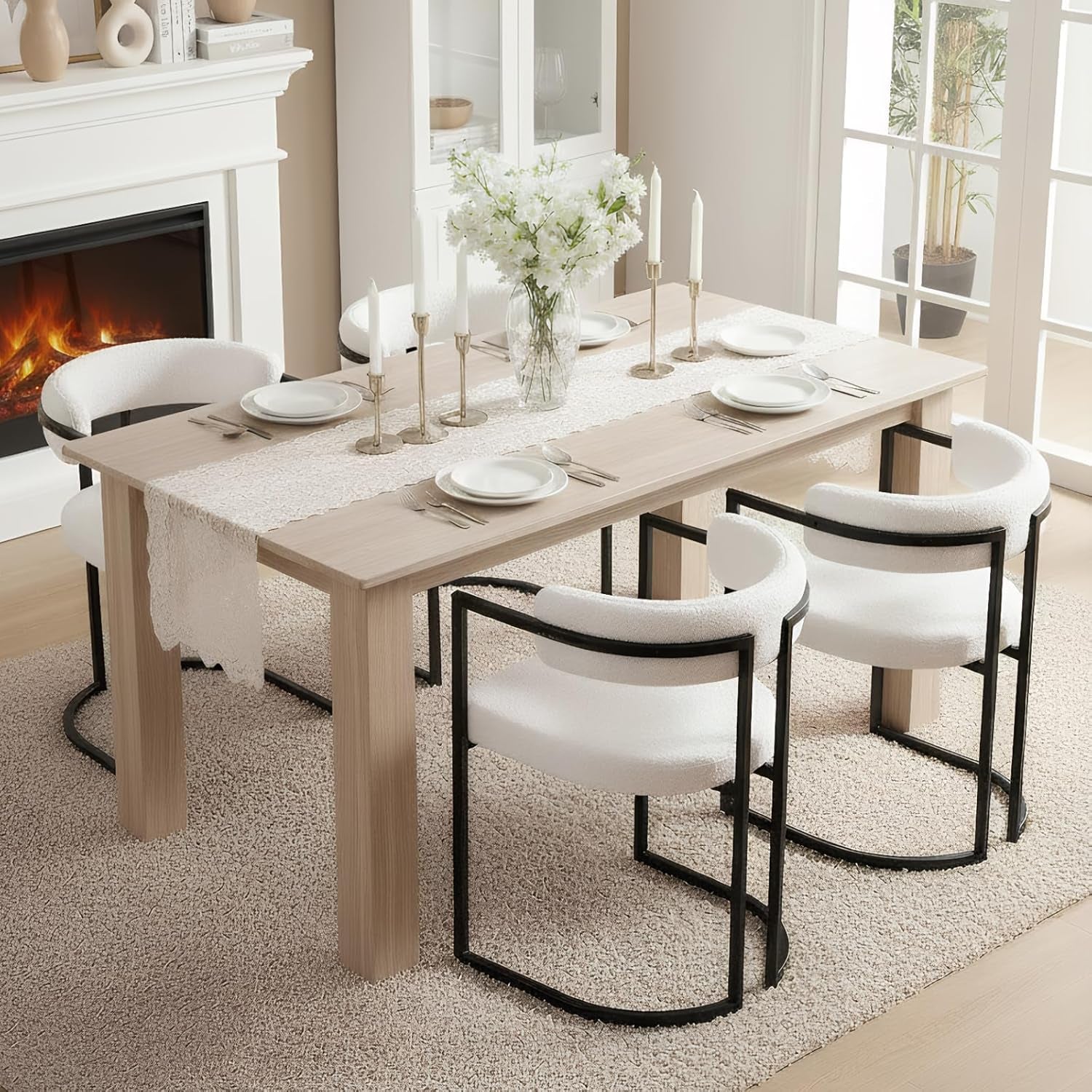 Dining room with a wooden table set for dinner, white chairs, and a fireplace.