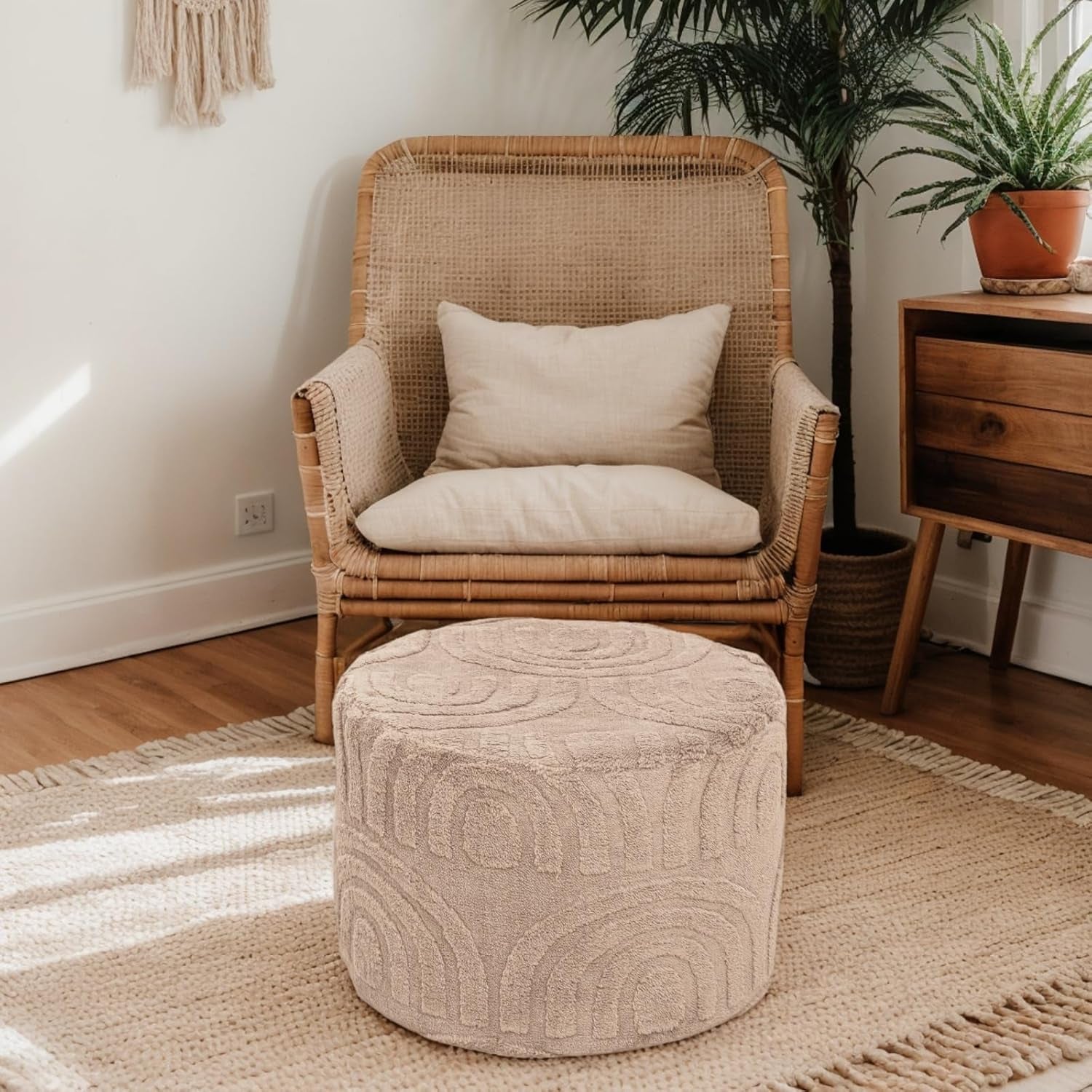 Wicker chair with a cushion and ottoman on a rug in a room with plants and wooden furniture.