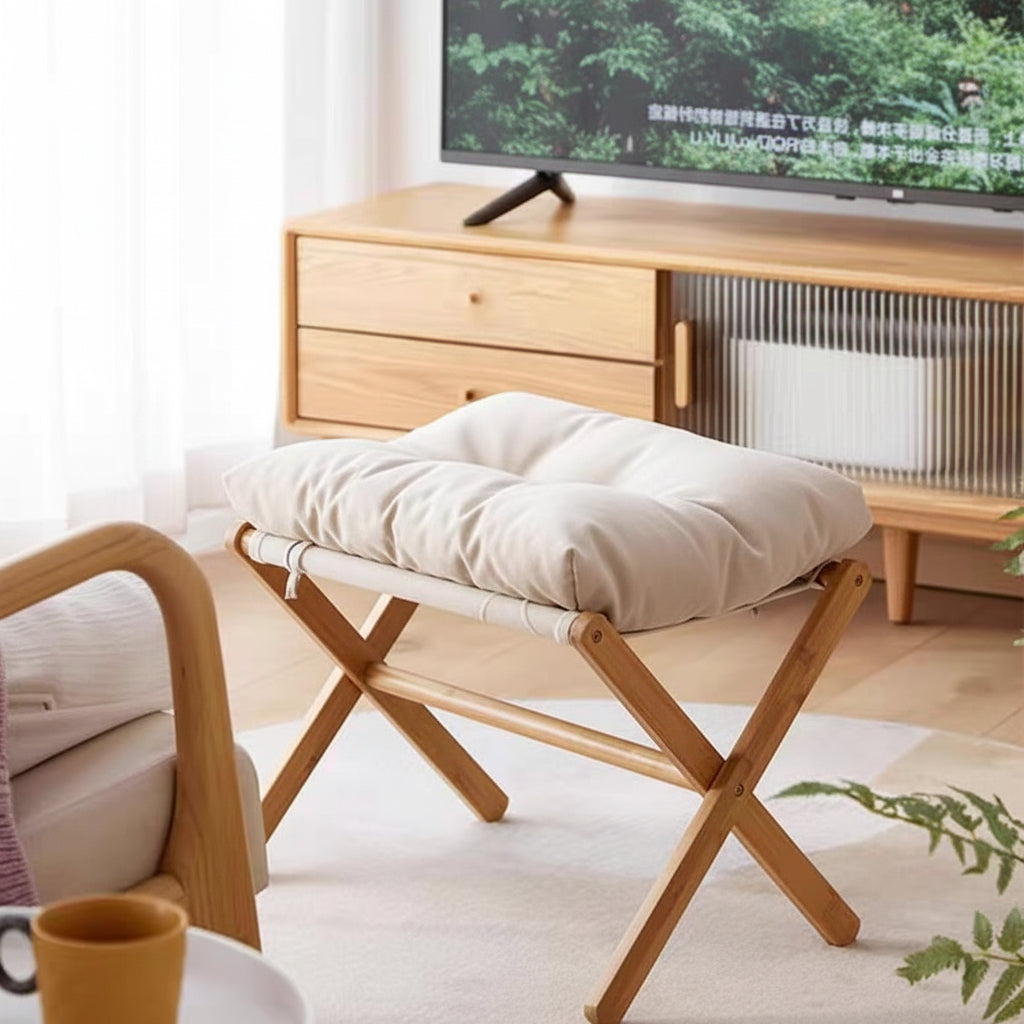 Person relaxing with feet up on a wooden footstool in a living room.
