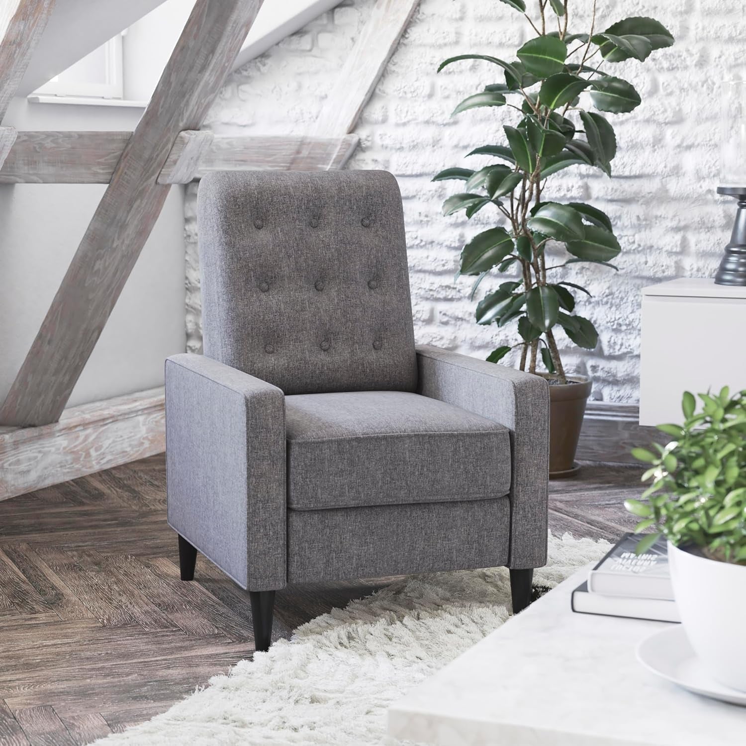 Gray armchair in a room with plants and wooden floor