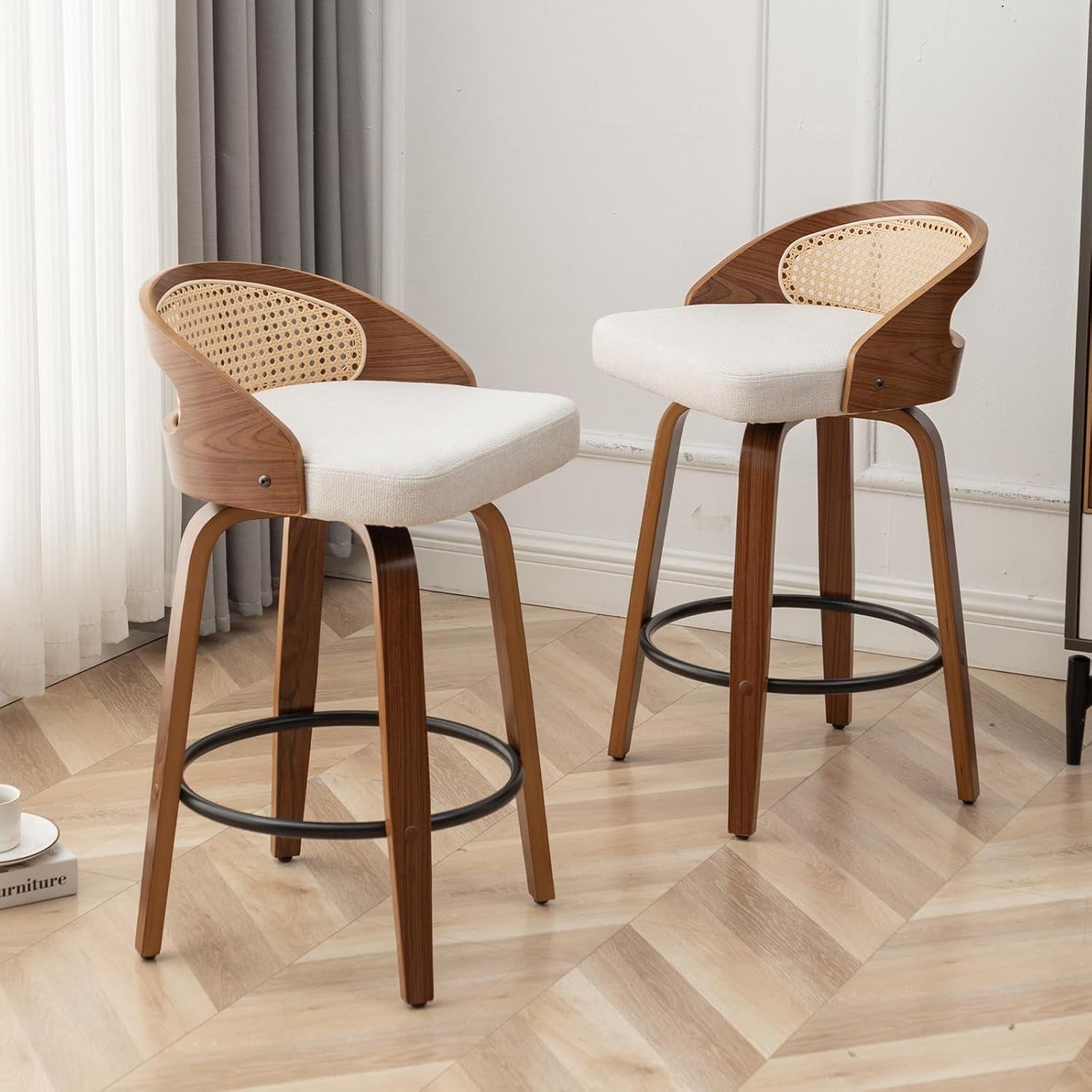Two wooden bar stools with white seats on a wooden floor.