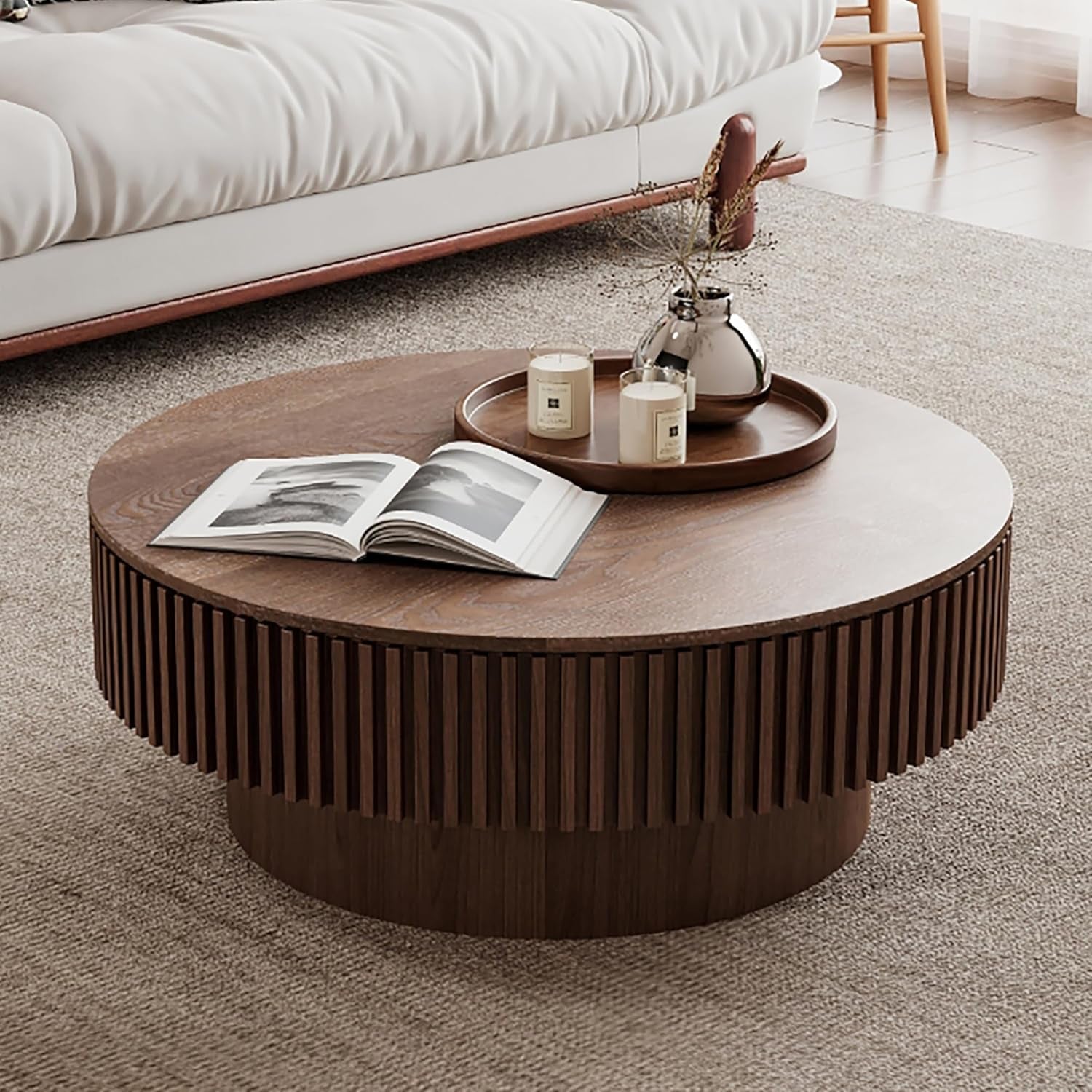 Round wooden coffee table with decorative items in a living room setting