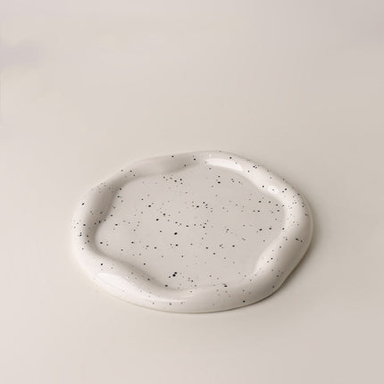 Speckled ceramic plate on a beige background