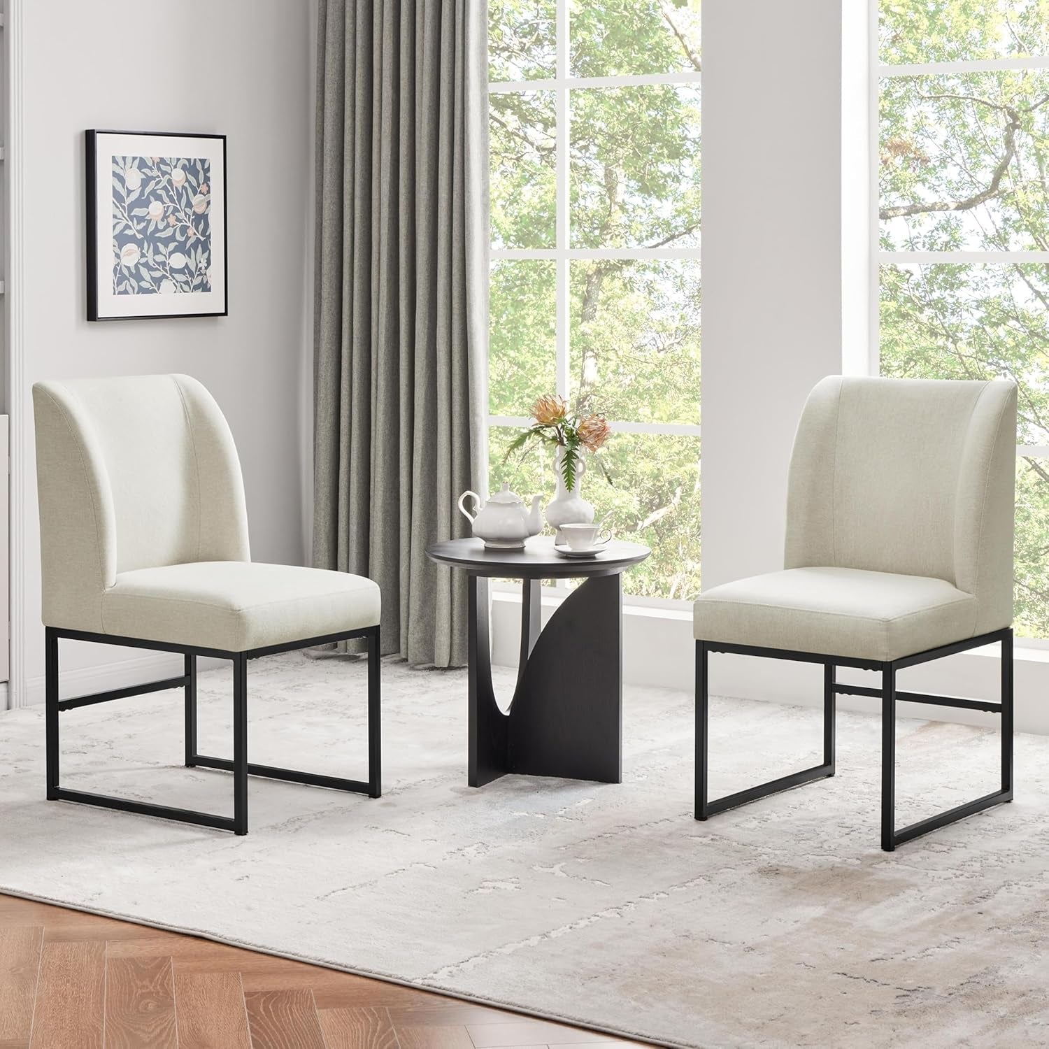 Two beige chairs with black metal legs in a room with large windows.