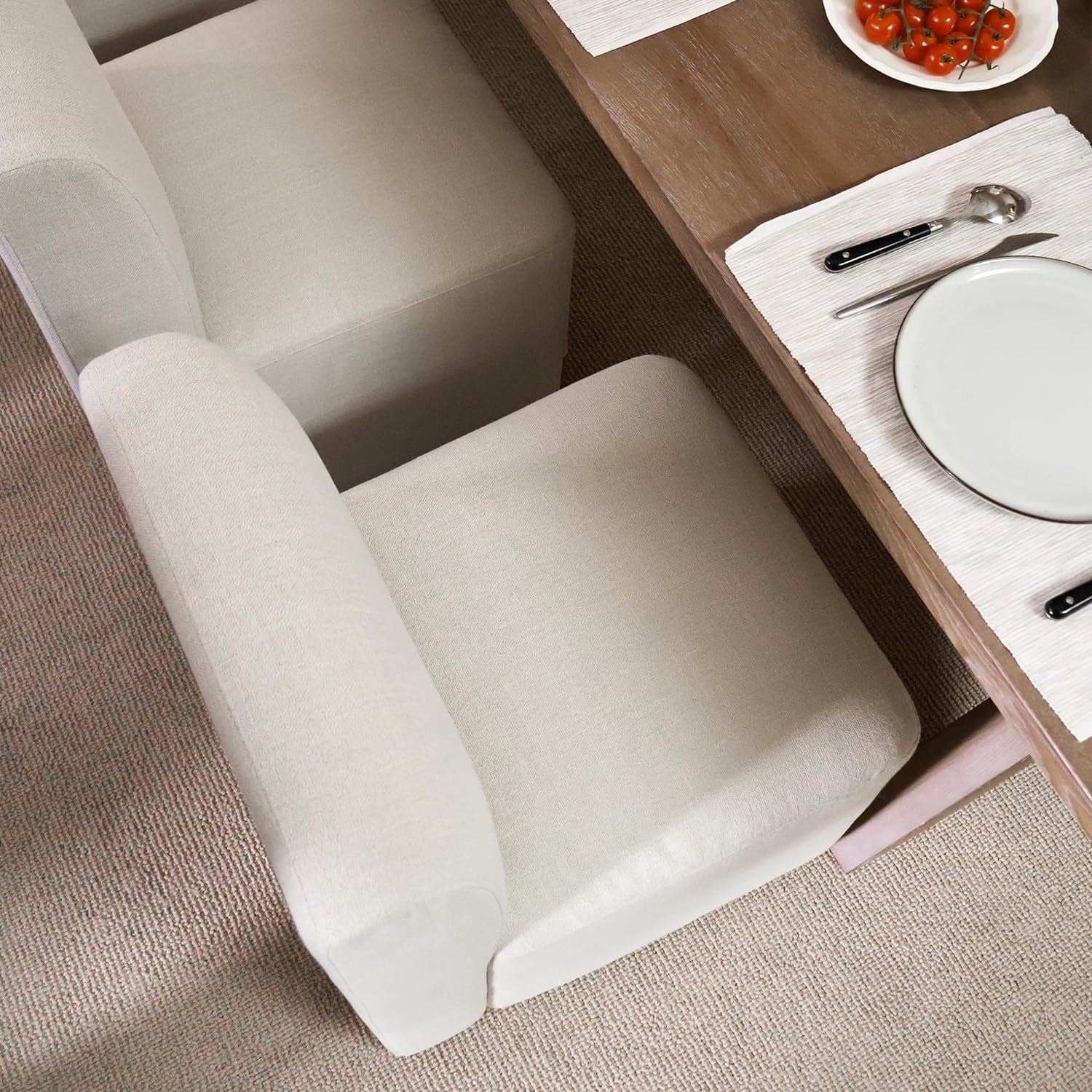 Beige armchair in a room with a table and plates.
