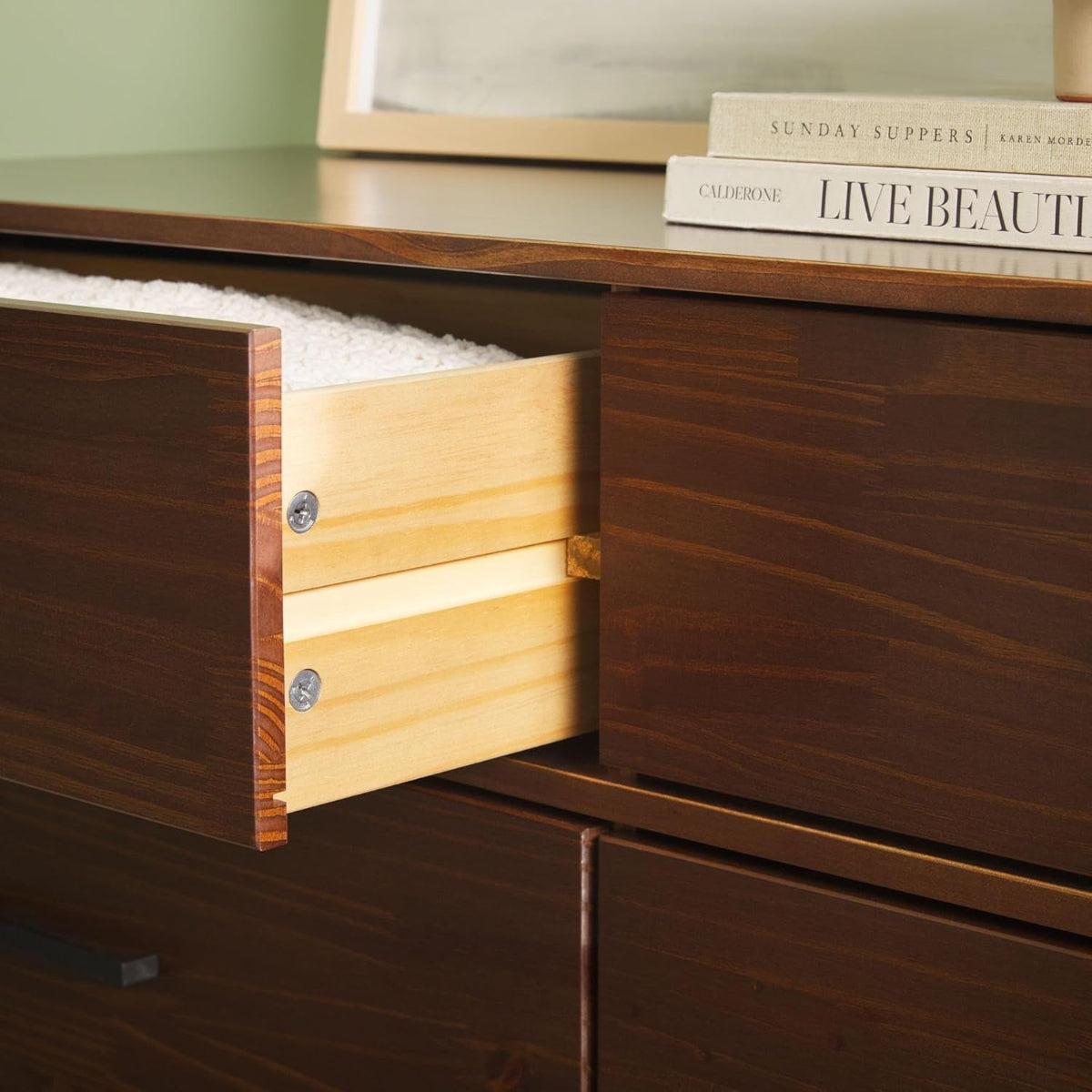 Wooden dresser with an open drawer, books on top