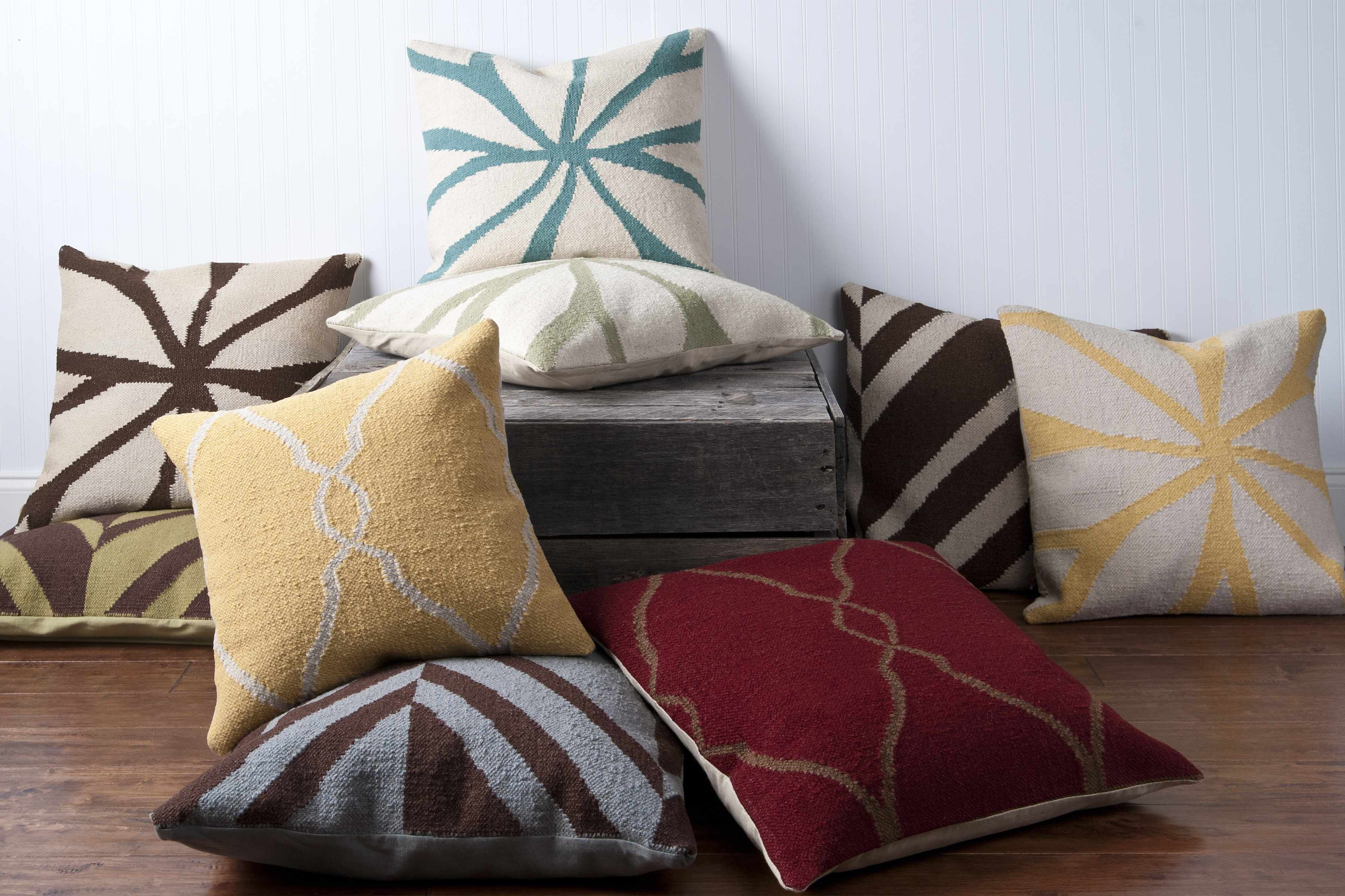 Collection of patterned cushions on a wooden surface with a white background