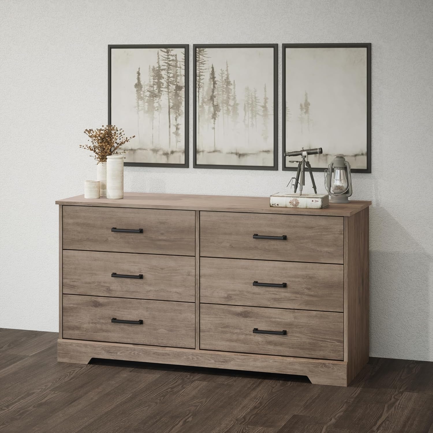 Wooden dresser with four drawers in a room with framed artwork on the wall.