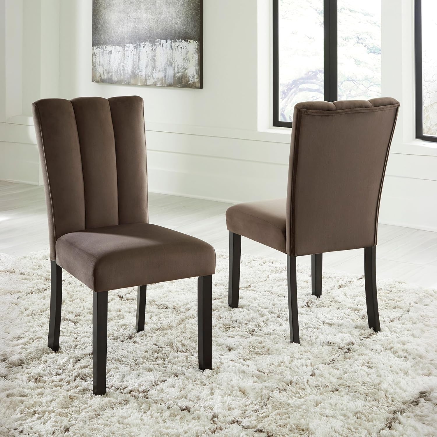 Two brown upholstered chairs on a white carpet in a room with large windows.