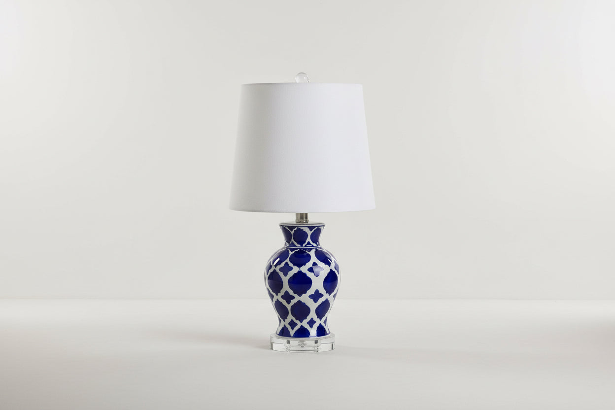 Table lamp with blue and white patterned base and white shade on a white background