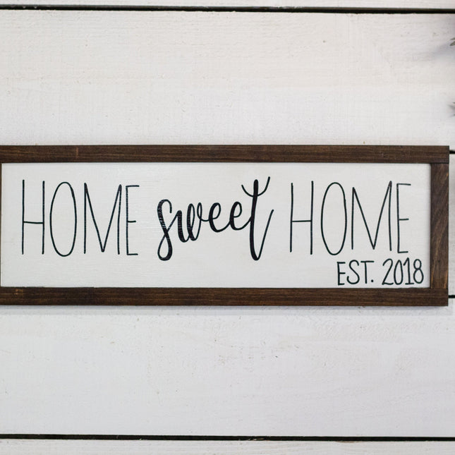 Decorative sign with 'Home sweet home' text on a white wooden background