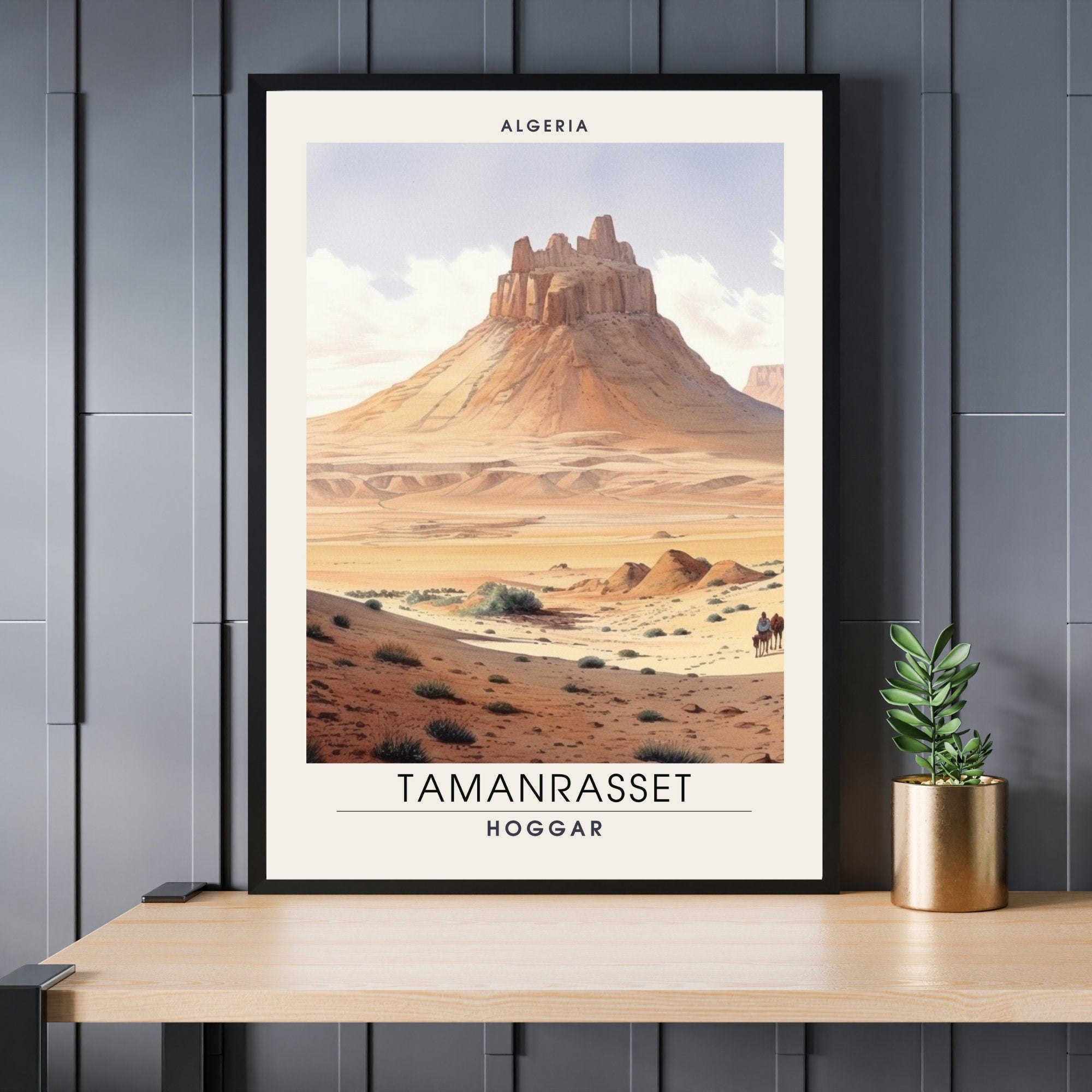 Framed poster of Tamanrasset, Hoggar, Algeria with desert landscape on a wooden table.