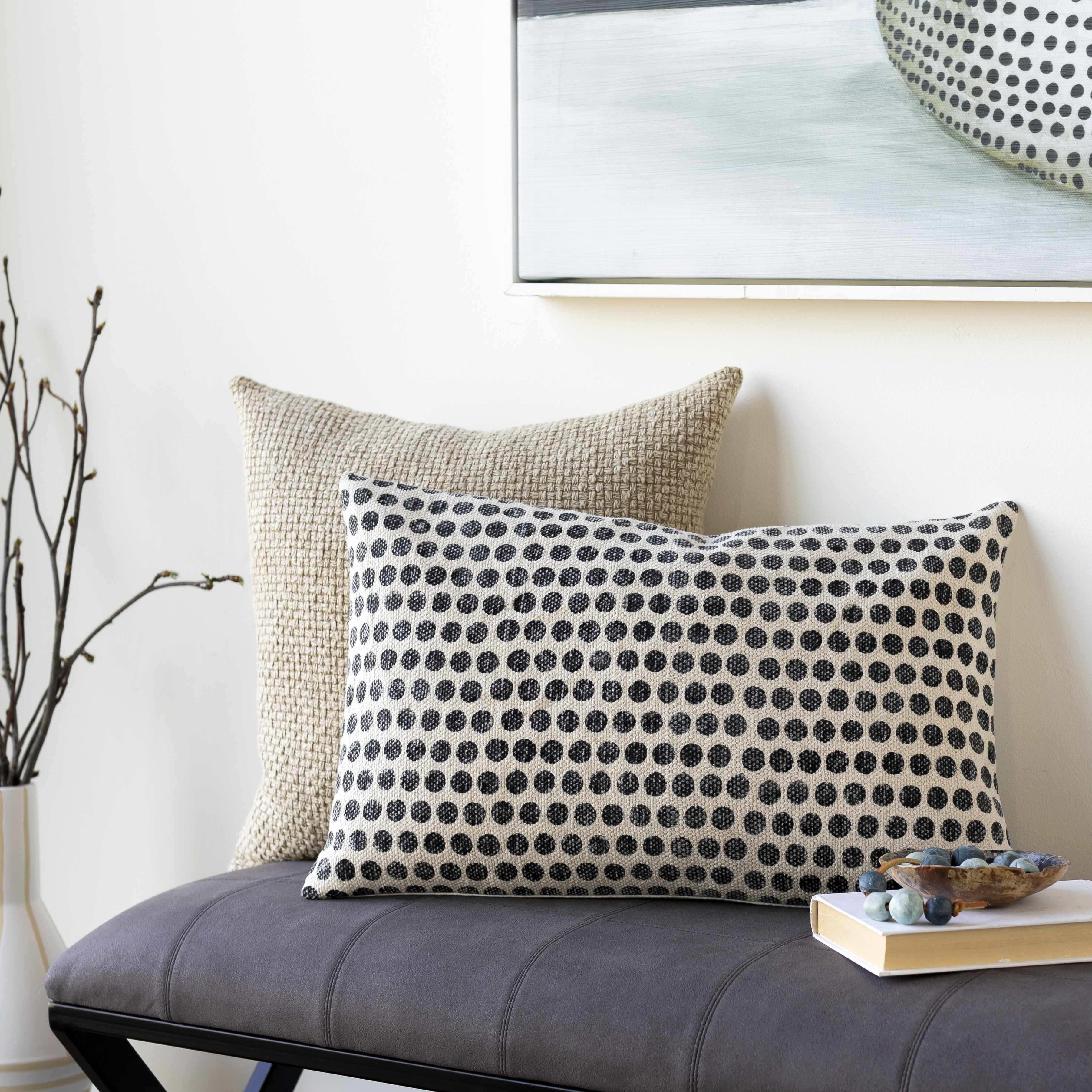 Two decorative pillows on a gray bench against a white wall.