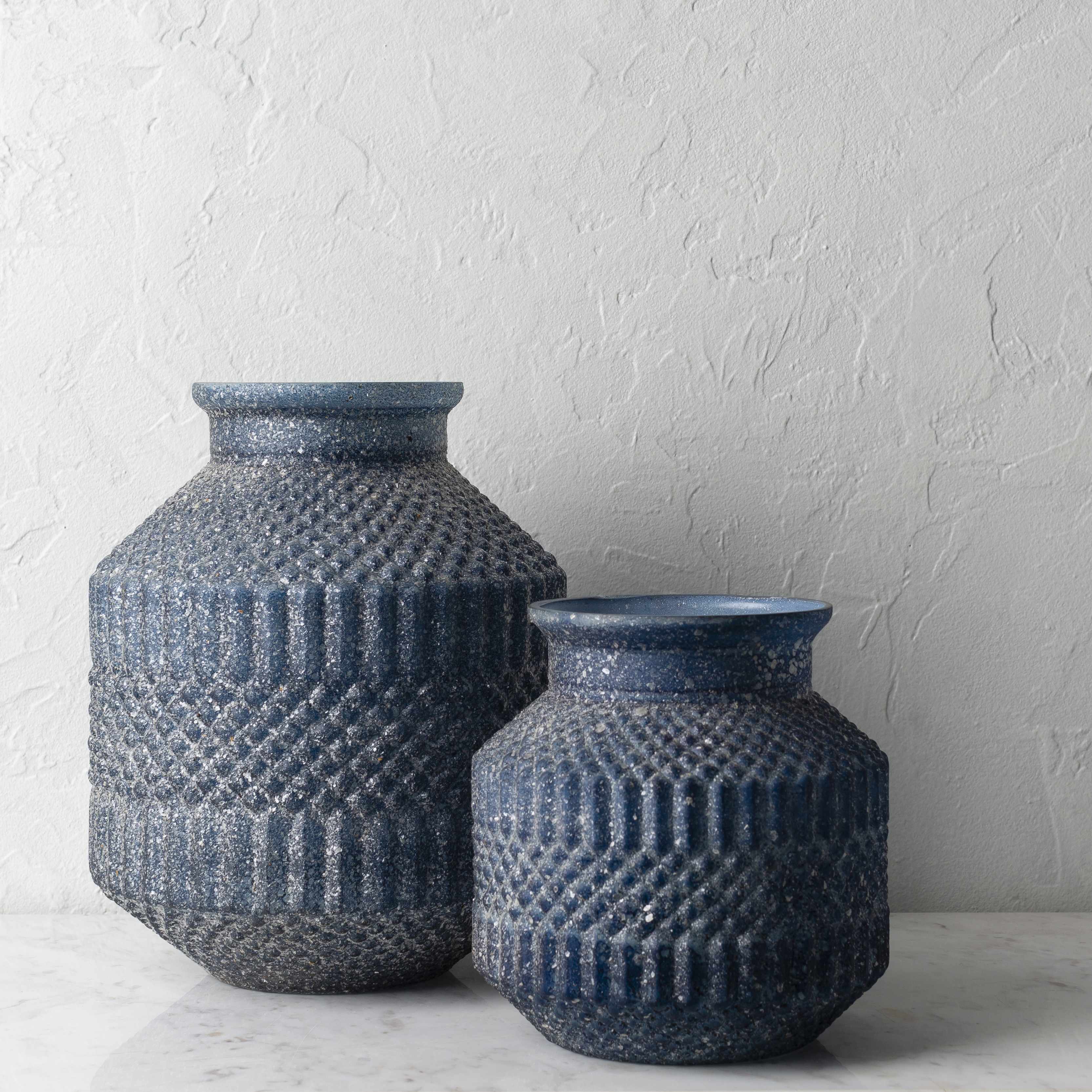 Two blue textured vases on a light surface with a white background