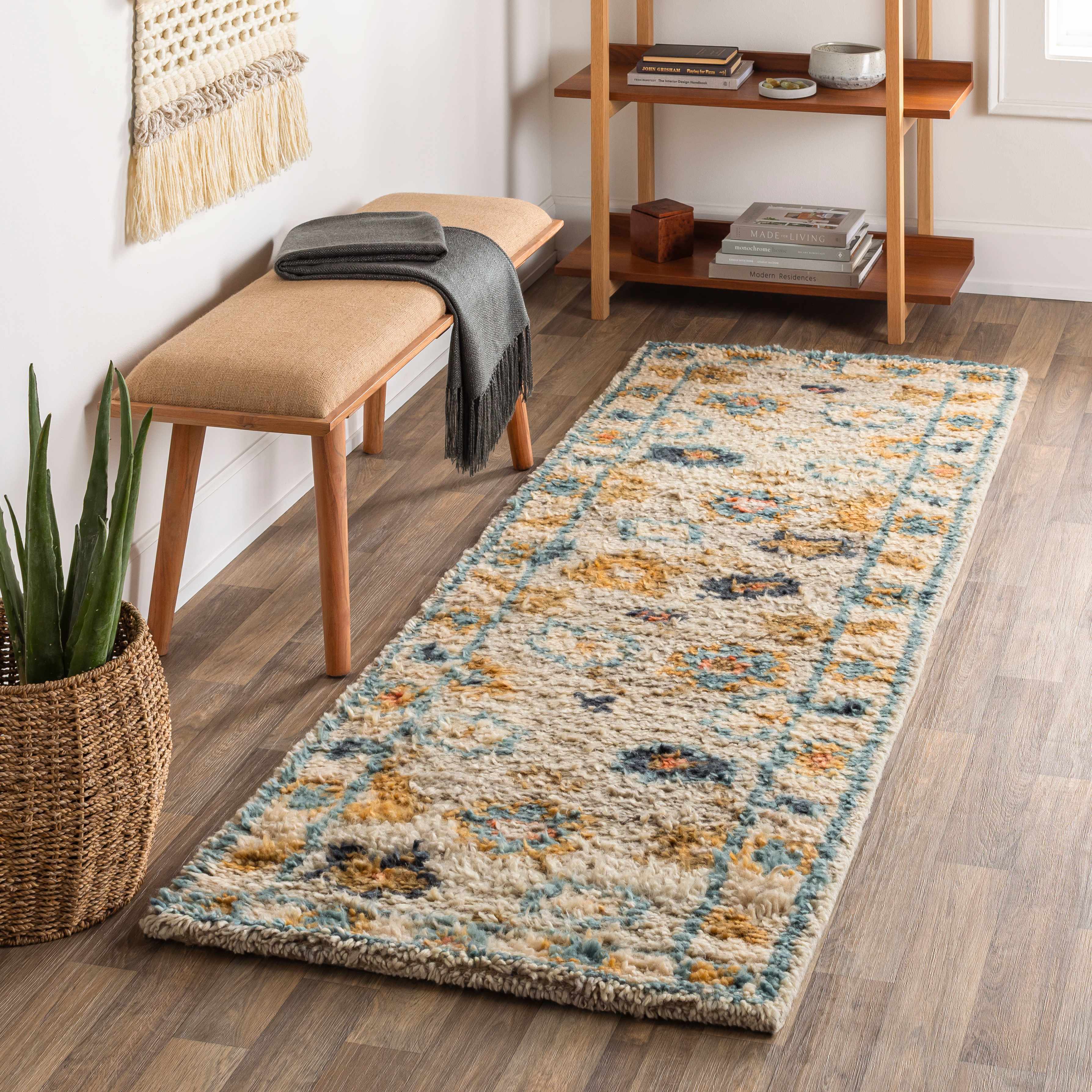 Long, patterned rug on a wooden floor with a bench and shelf in the background.