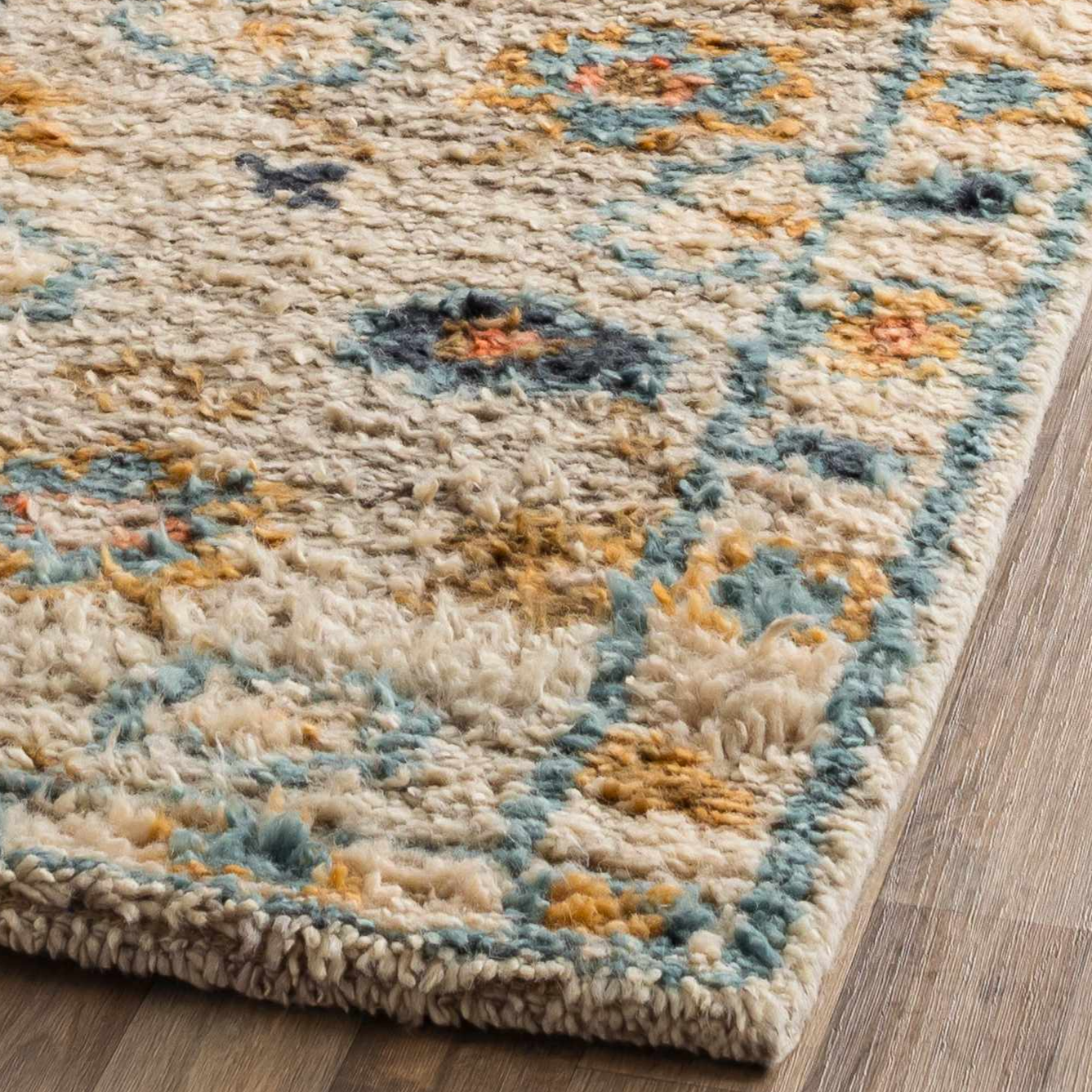 Close-up of a textured area rug with floral patterns on a wooden floor.