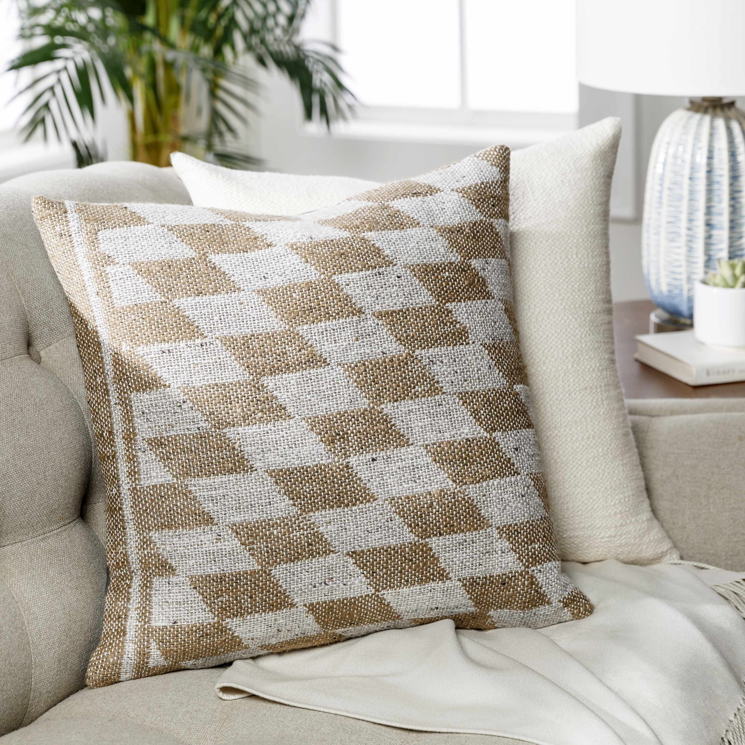 Decorative pillow with a checkered pattern on a couch in a living room setting.