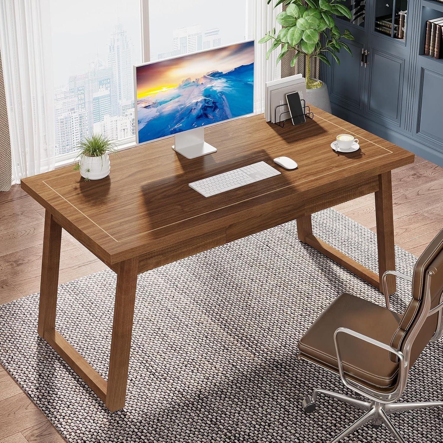 Wooden desk with office setup including a computer monitor, keyboard, and chair in a room with large windows.