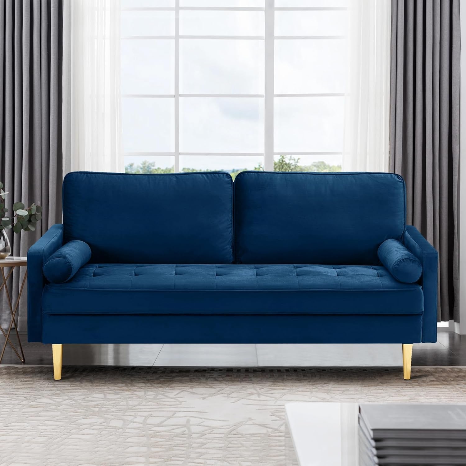 Blue sofa in a living room with large windows and curtains.