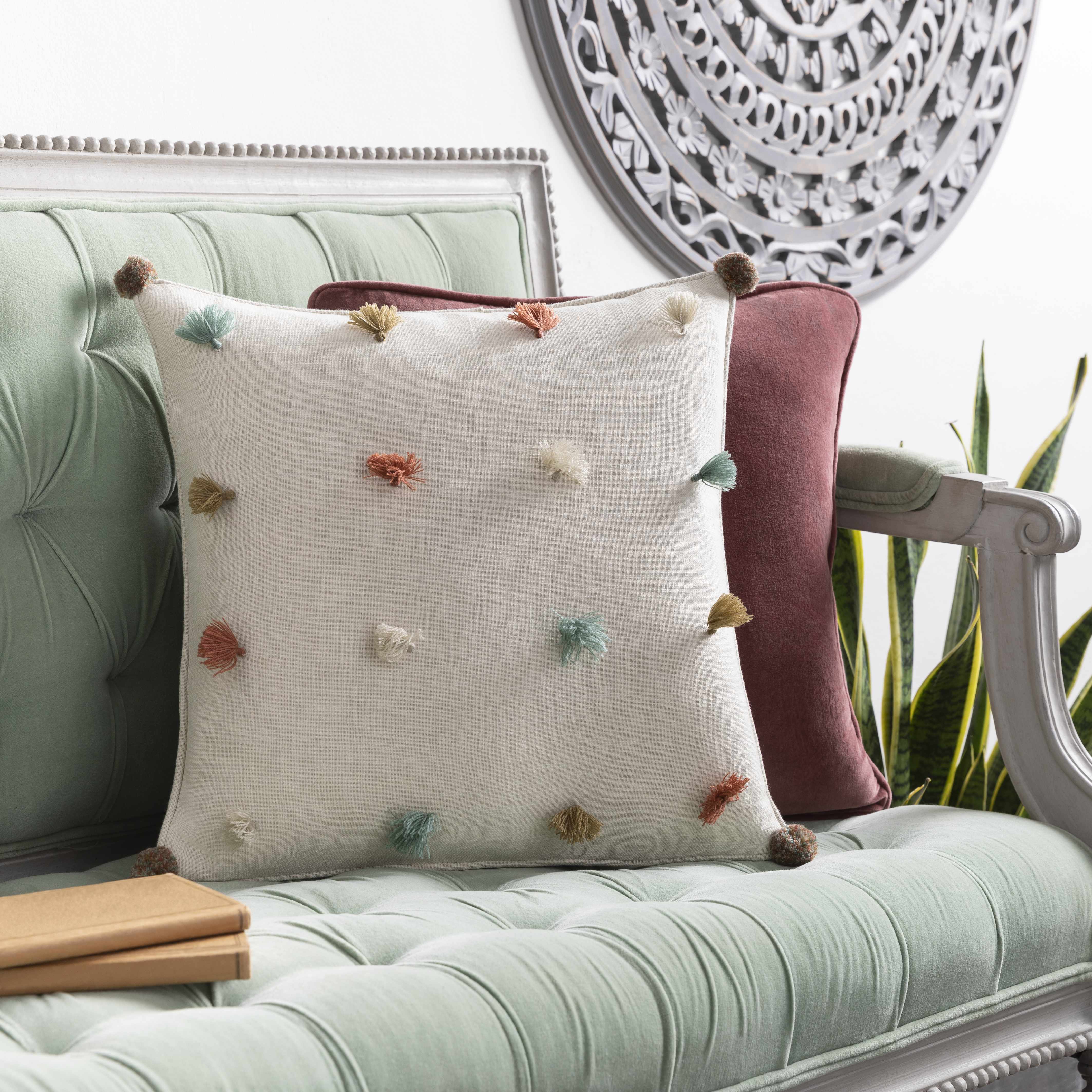 Decorative pillow with colorful pom-poms on a light green sofa