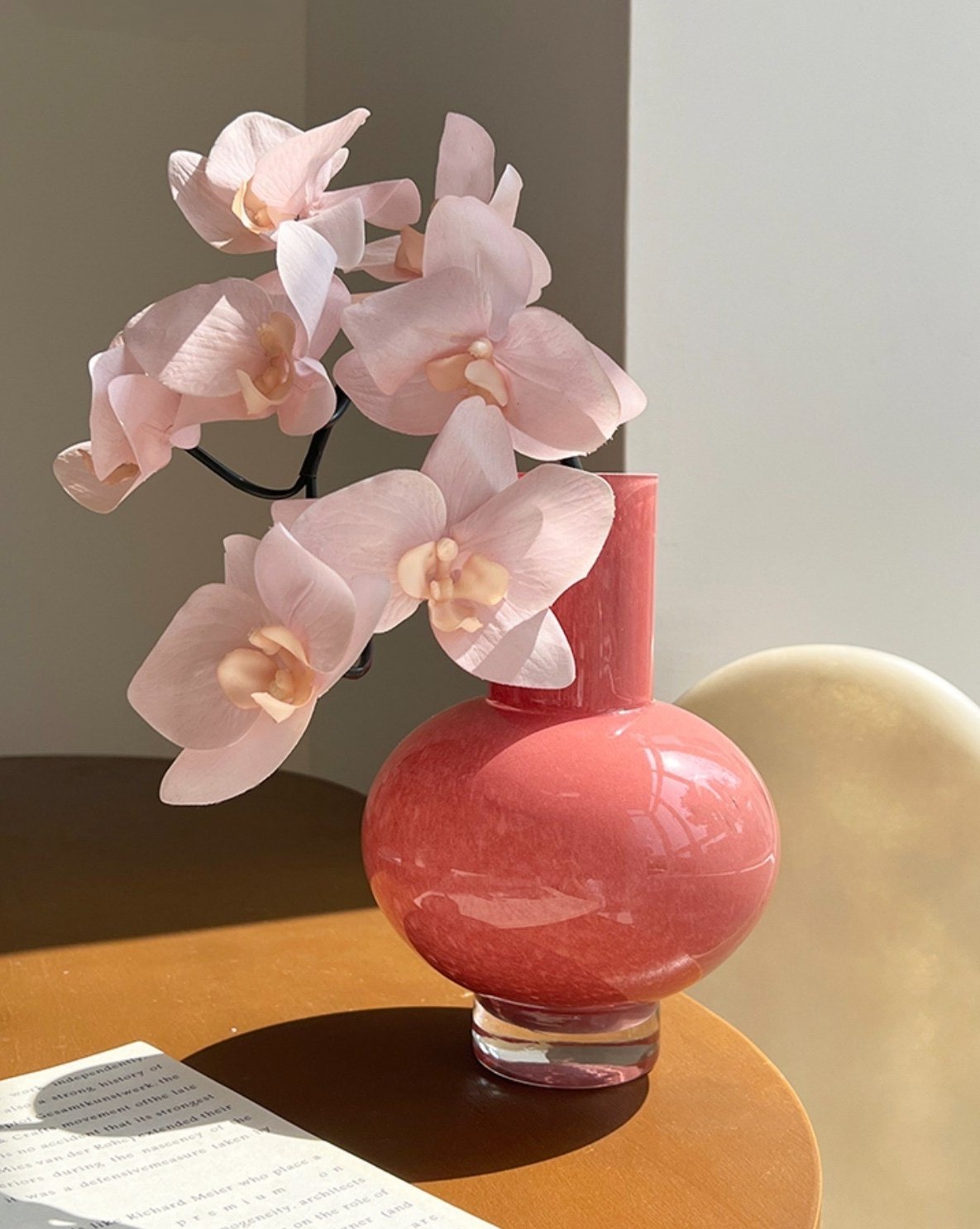 Pink vase with pink orchids on a wooden surface