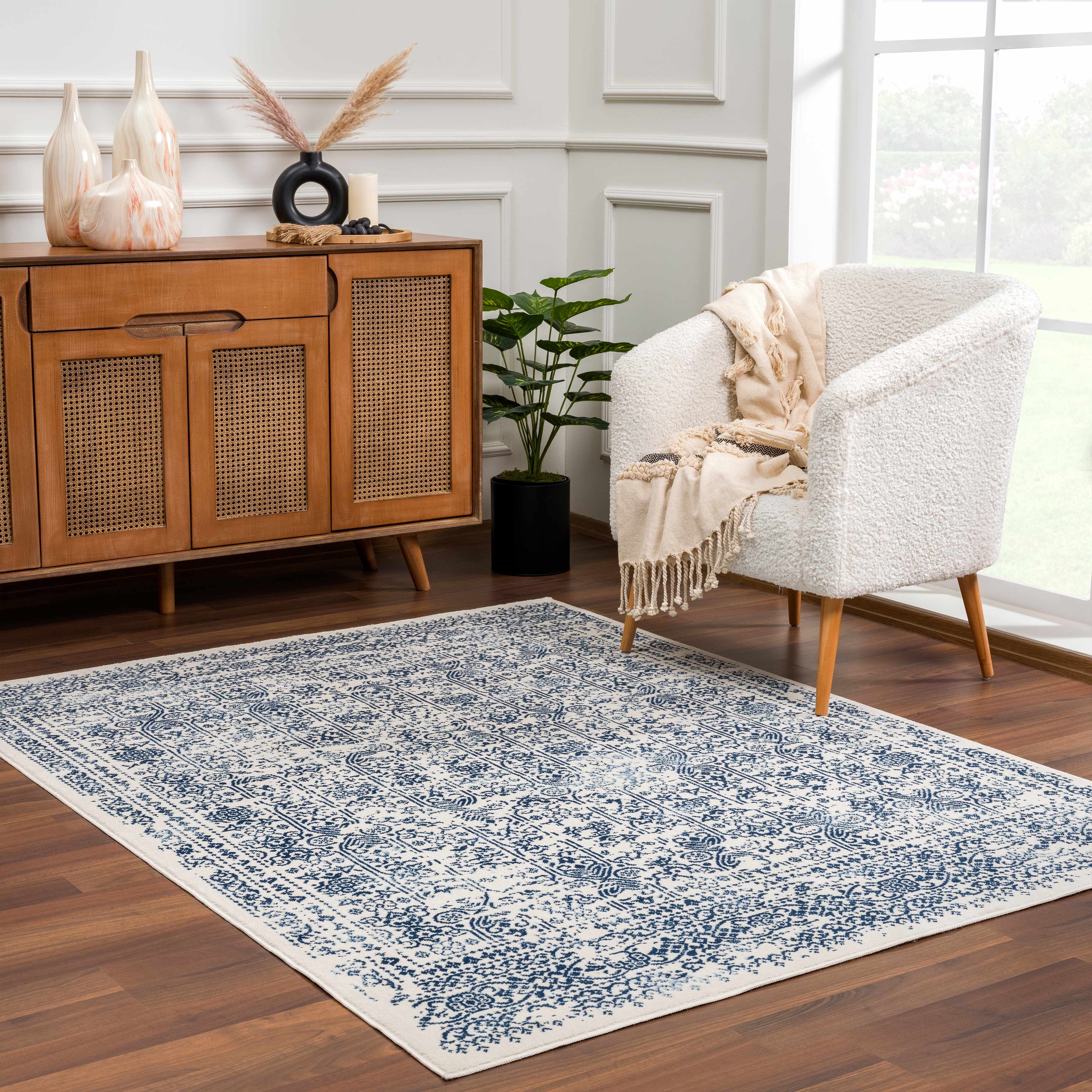 Living room with a blue and white patterned rug, wooden sideboard, and armchair.