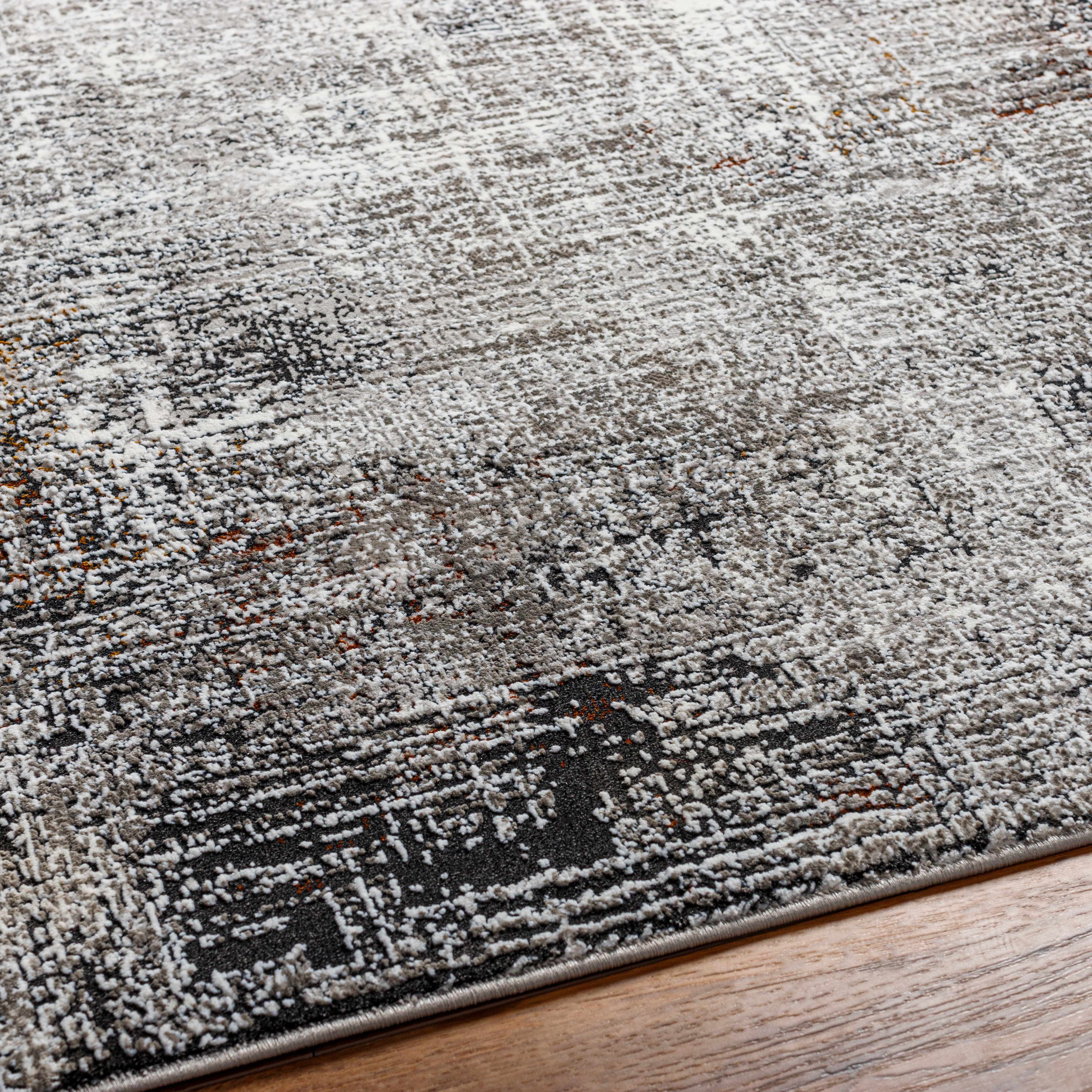 Close-up of a textured area rug with geometric pattern on a wooden floor.