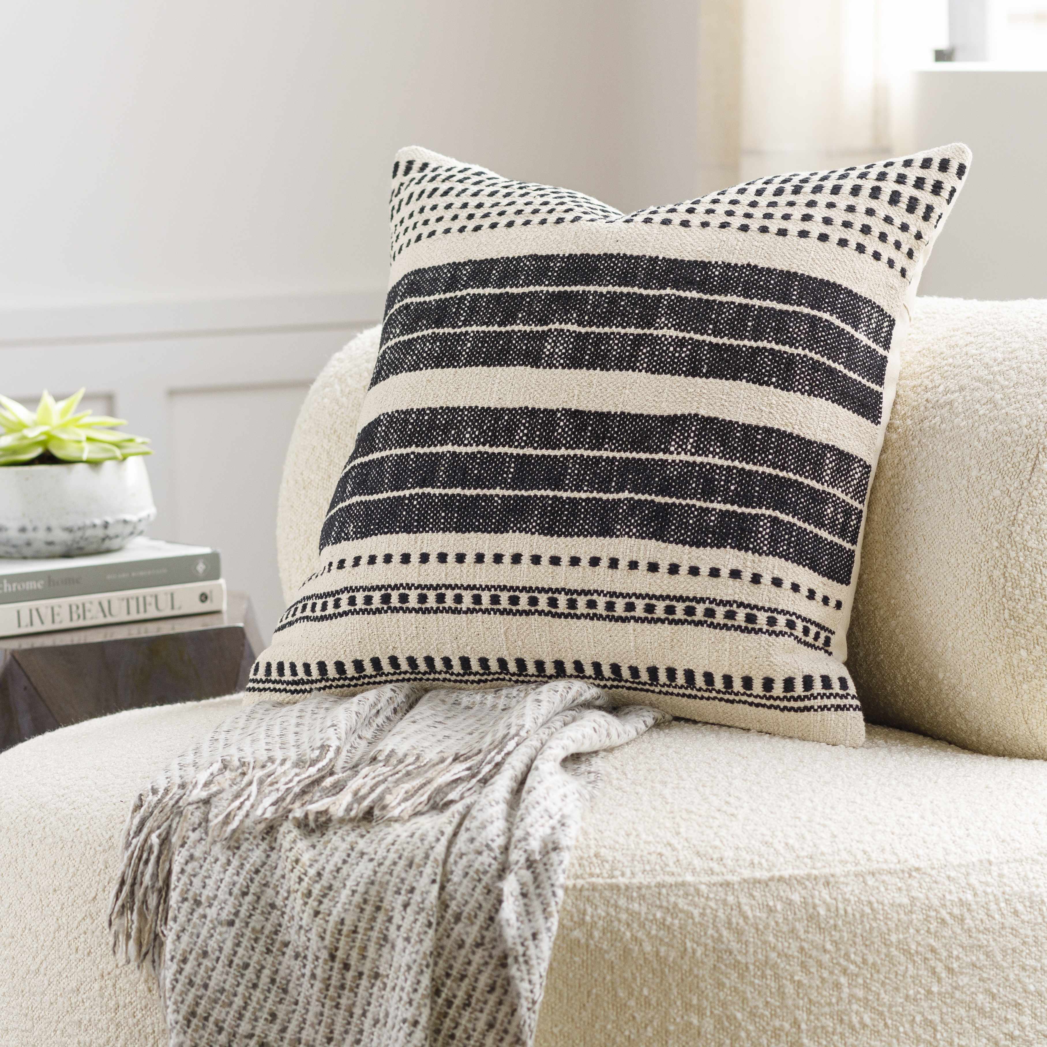 Decorative pillow with black and white stripes on a beige couch