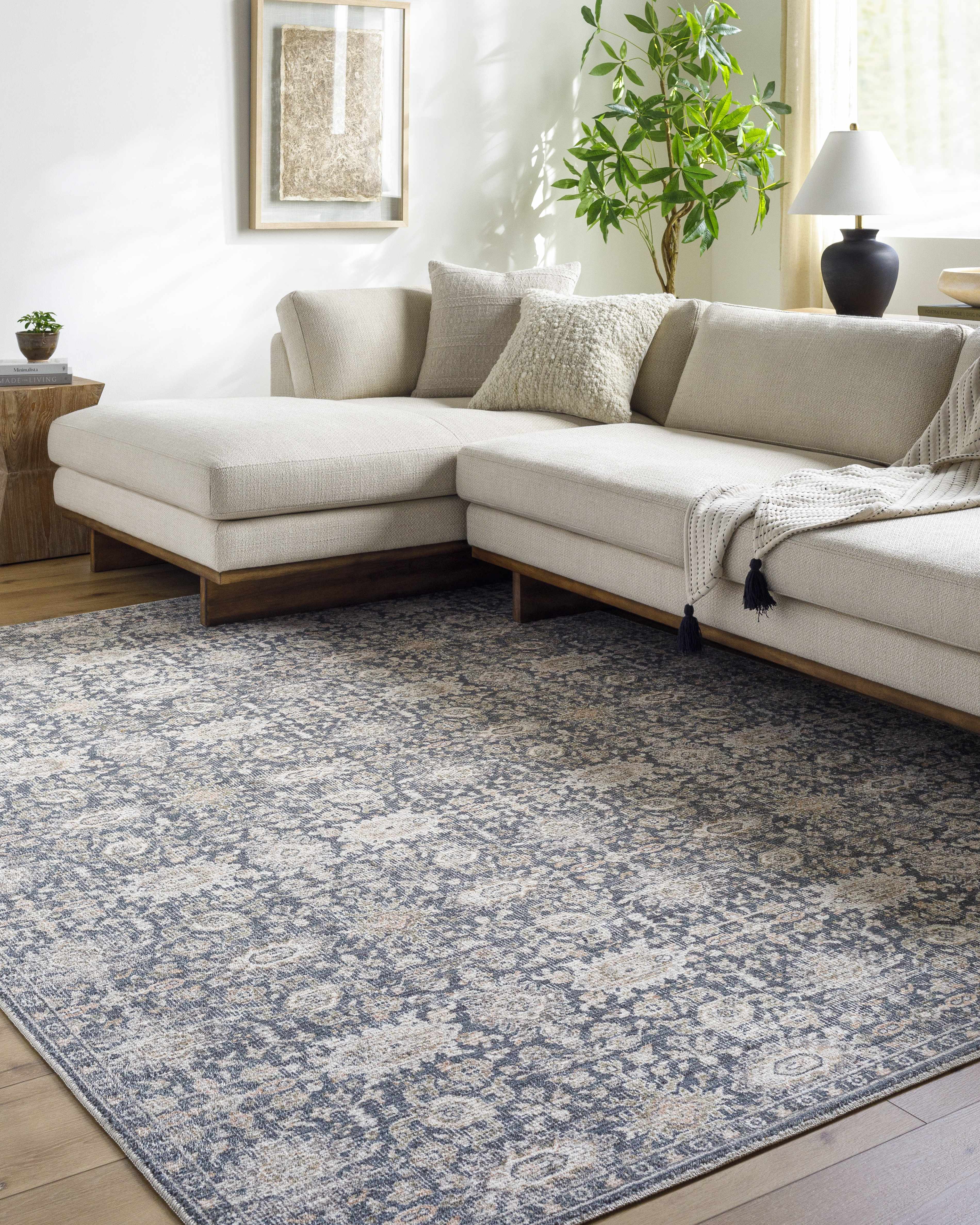 Beige sectional sofa in a living room with a patterned blue rug.