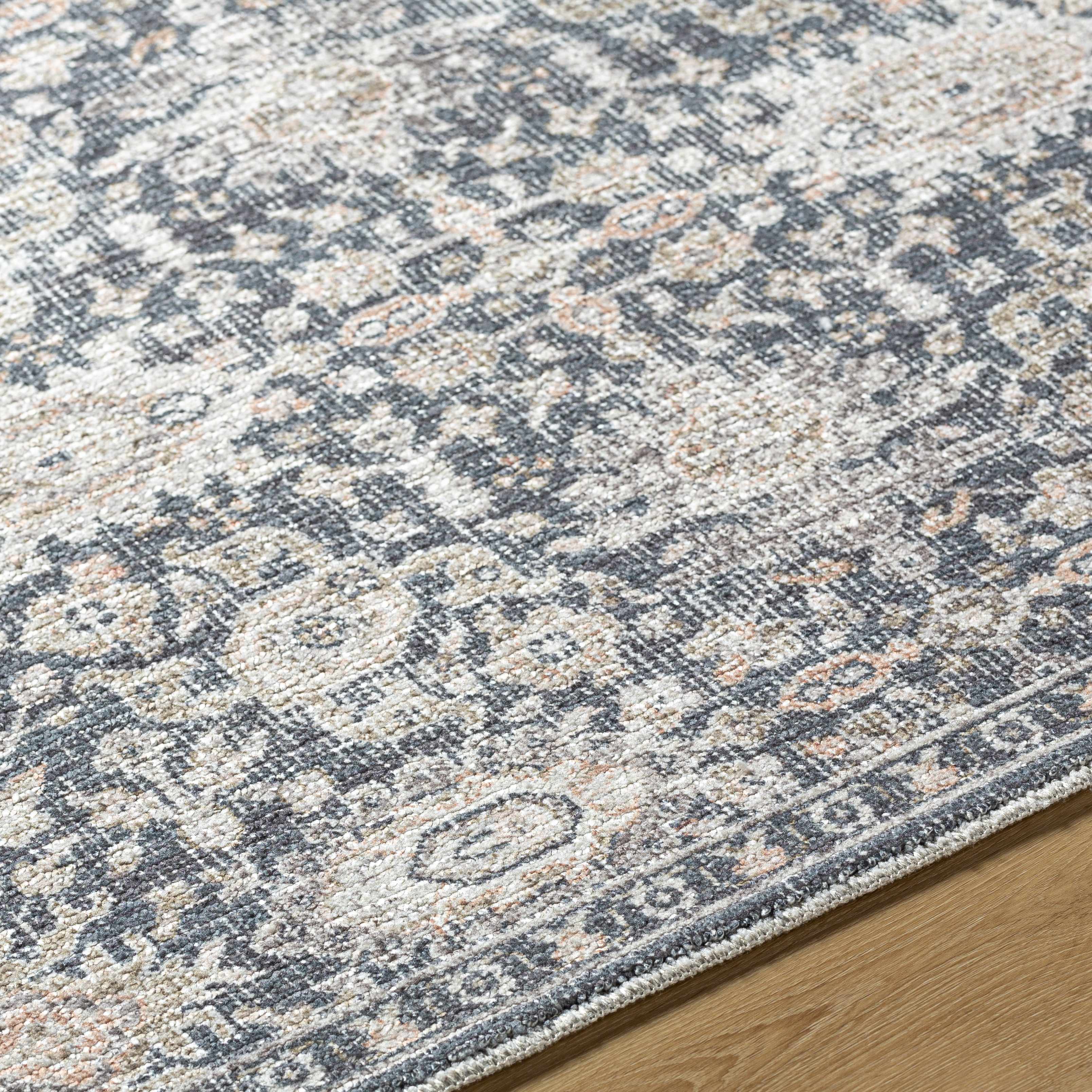 Close-up of a patterned rug with blue and beige colors on a wooden floor.