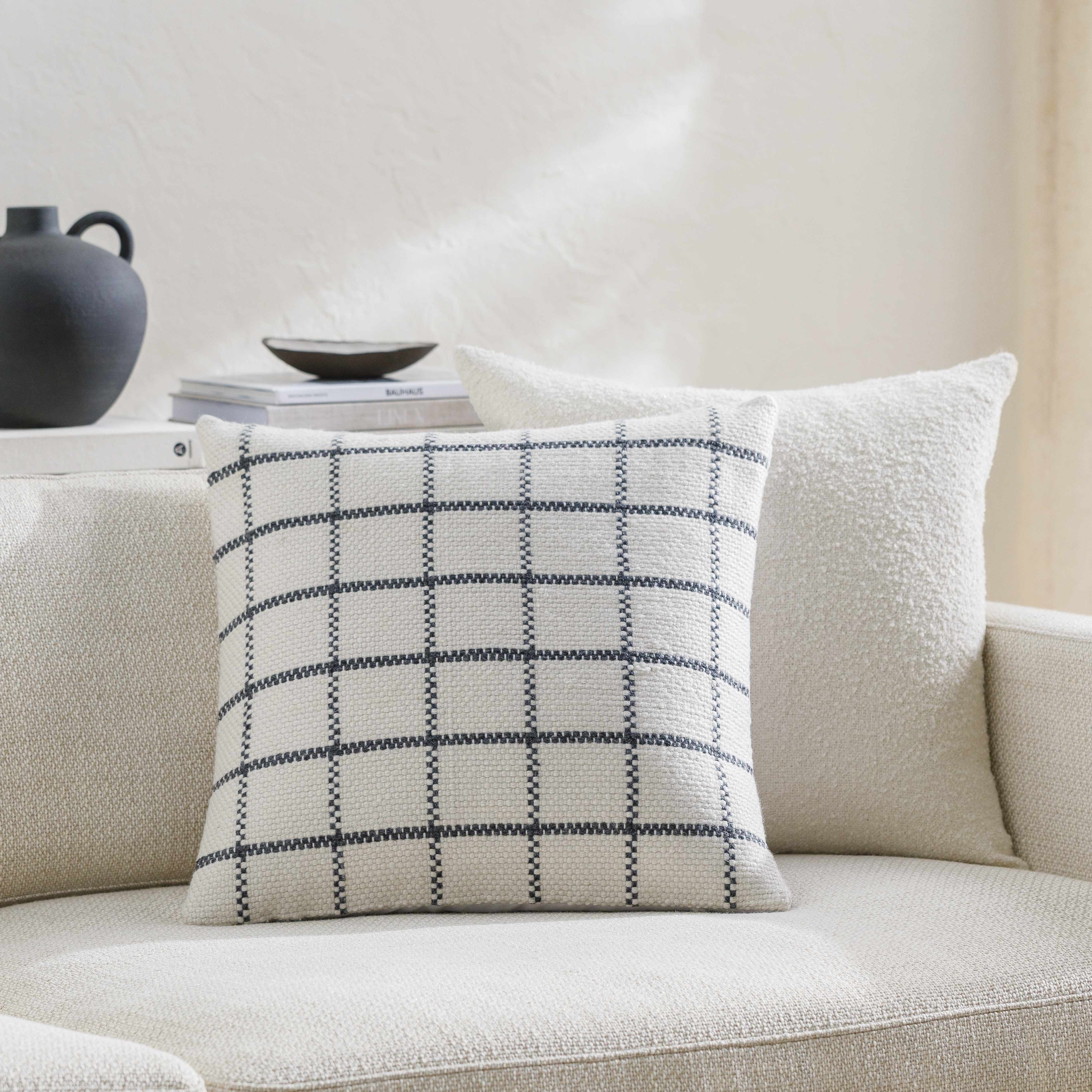 Plaid pillow on a beige sofa with a neutral background