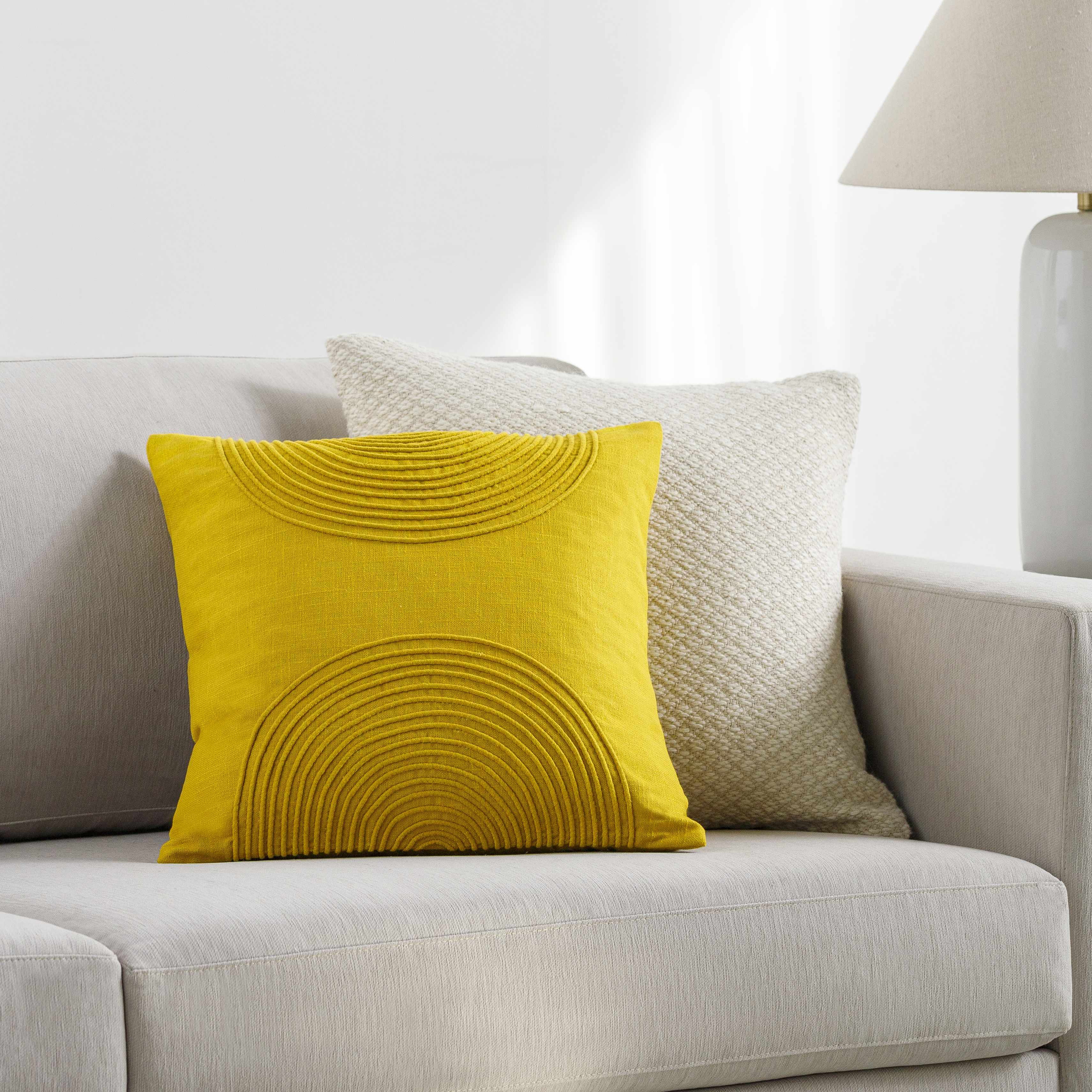 Yellow textured pillow on a gray sofa with a neutral background