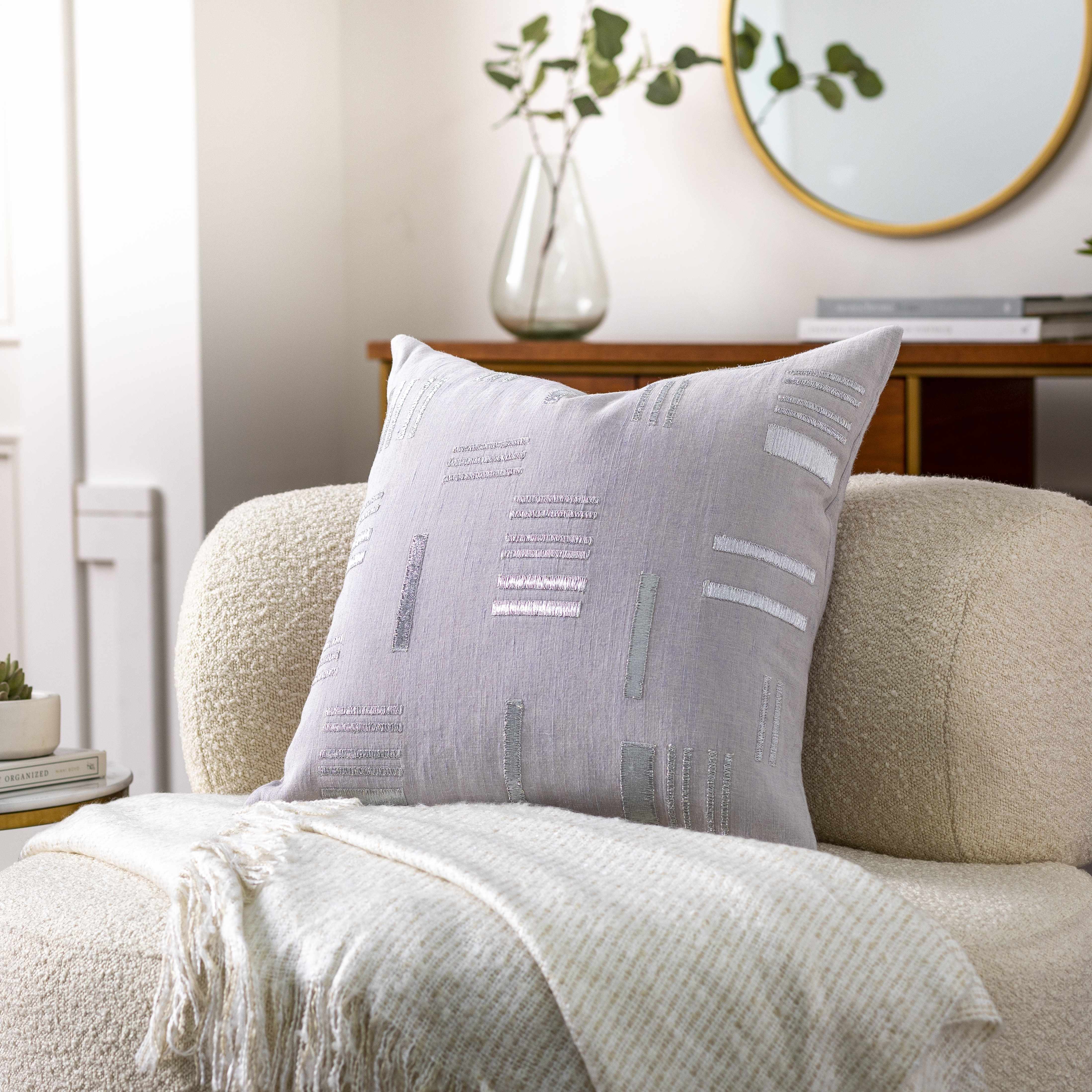 Gray textured pillow on a beige sofa with a neutral background