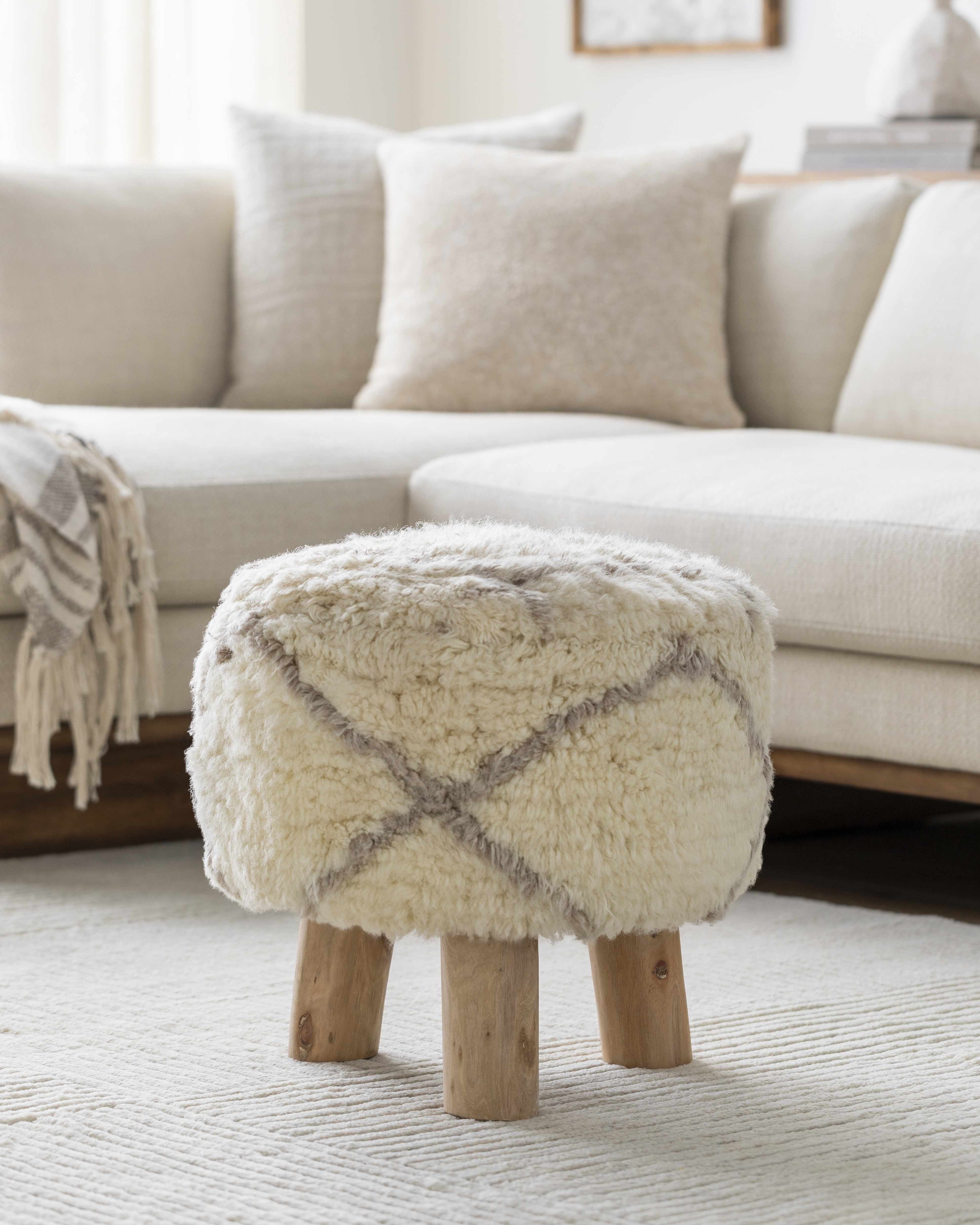 Fuzzy ottoman with wooden legs in a living room setting